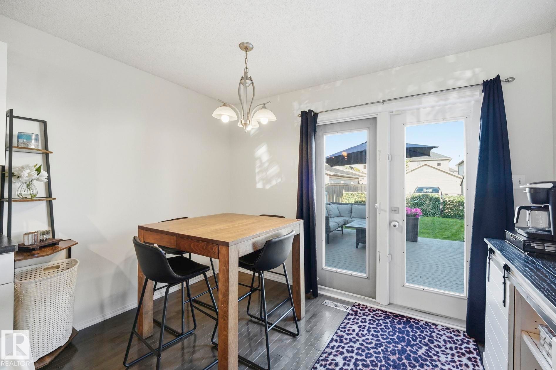 Dining area featuring dark wood-finish flooring, a contemporary chandelier, and white walls - 215 85 Street Sw, Edmonton, AB - Indoor