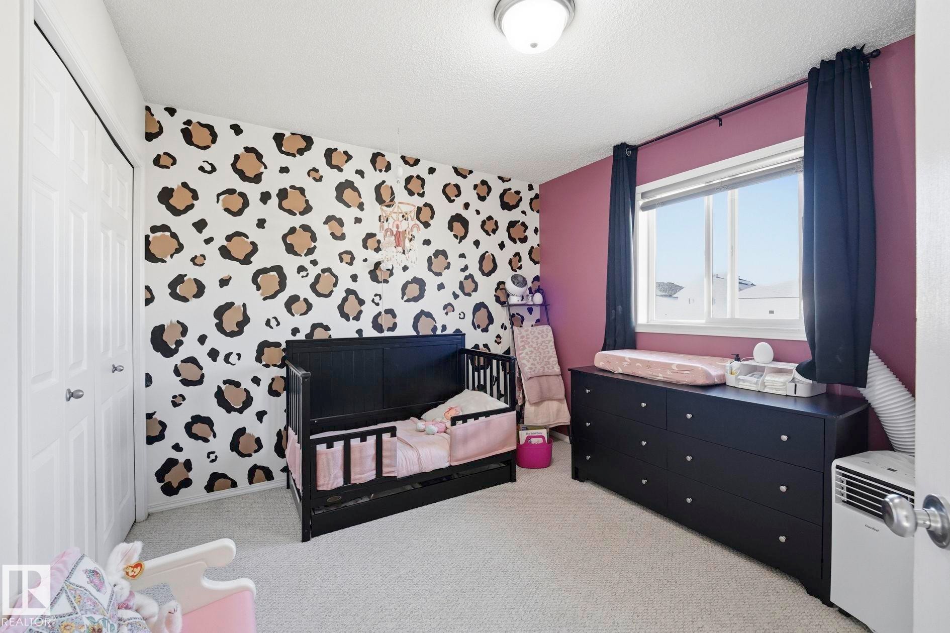 Carpeted interior with a window featuring a white frame, a textured ceiling, a flush mount light fixture, and a two-panel closet door - 215 85 Street Sw, Edmonton, AB - Indoor Photo Showing Bedroom