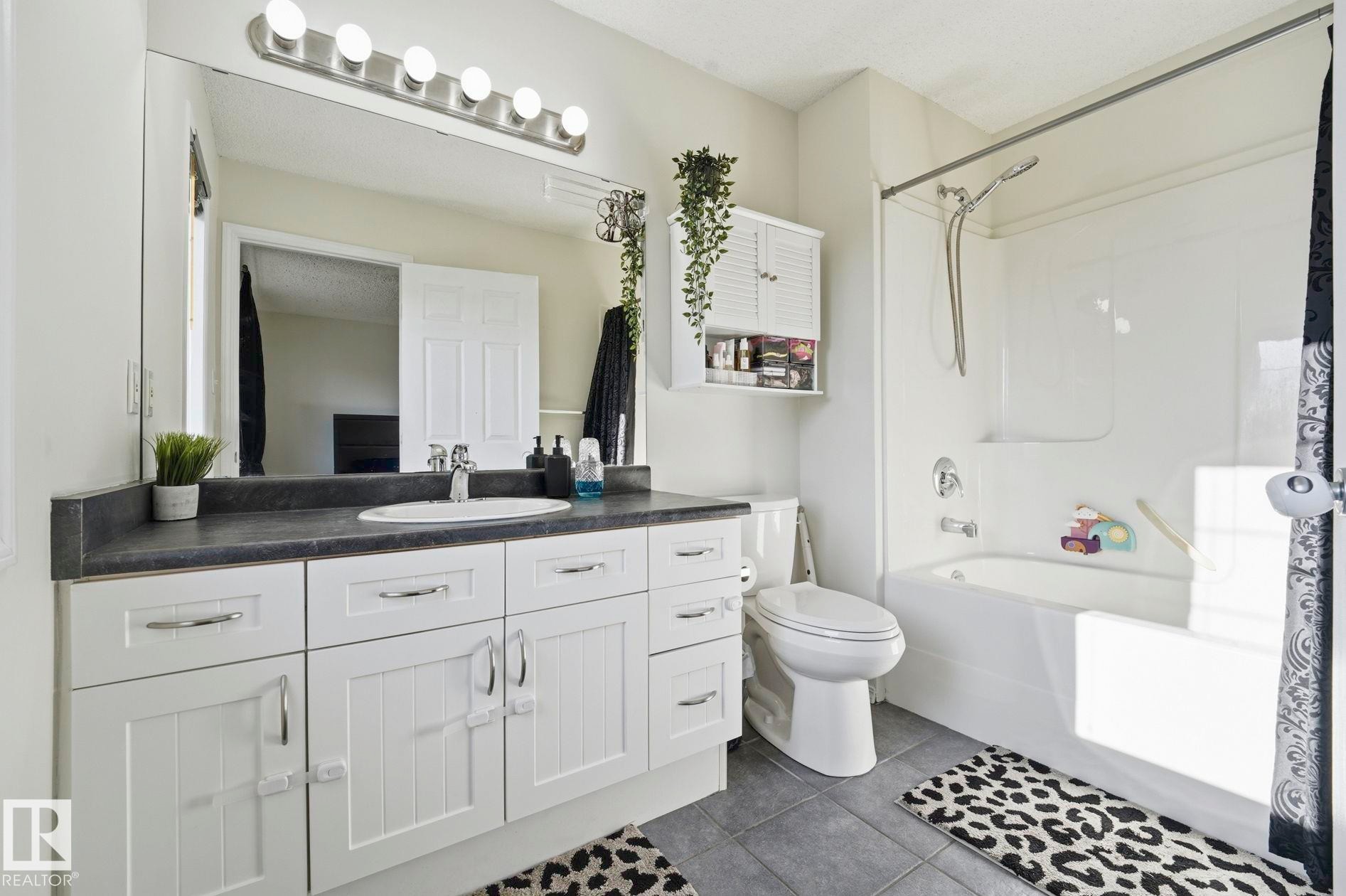 Modern bathroom featuring a single white vanity with an undermount sink, dark countertop, and brushed nickel hardware - 215 85 Street Sw, Edmonton, AB - Indoor Photo Showing Bathroom