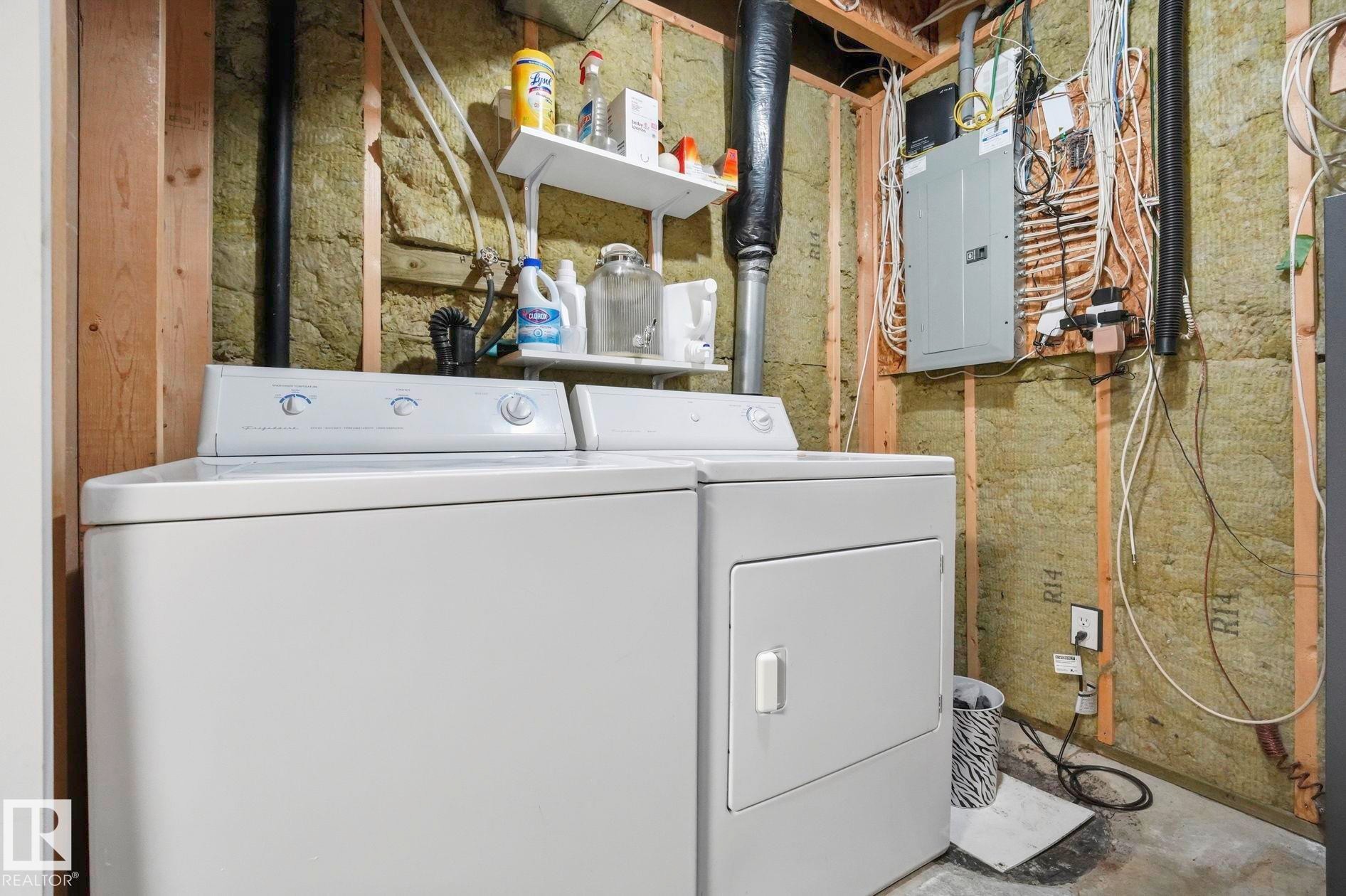 Utility area with a white washer and dryer pair, an electrical panel, and exposed wall insulation - 215 85 Street Sw, Edmonton, AB - Indoor Photo Showing Laundry Room