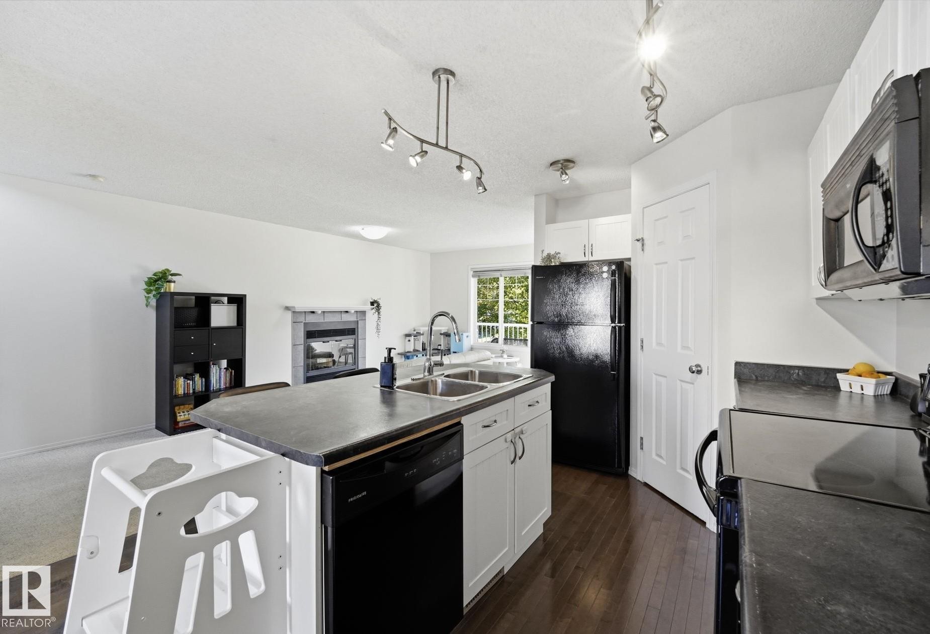 Open-concept kitchen featuring dark wood-finish flooring, white cabinetry, and a double basin sink - 215 85 Street Sw, Edmonton, AB - Indoor Photo Showing Kitchen With Double Sink