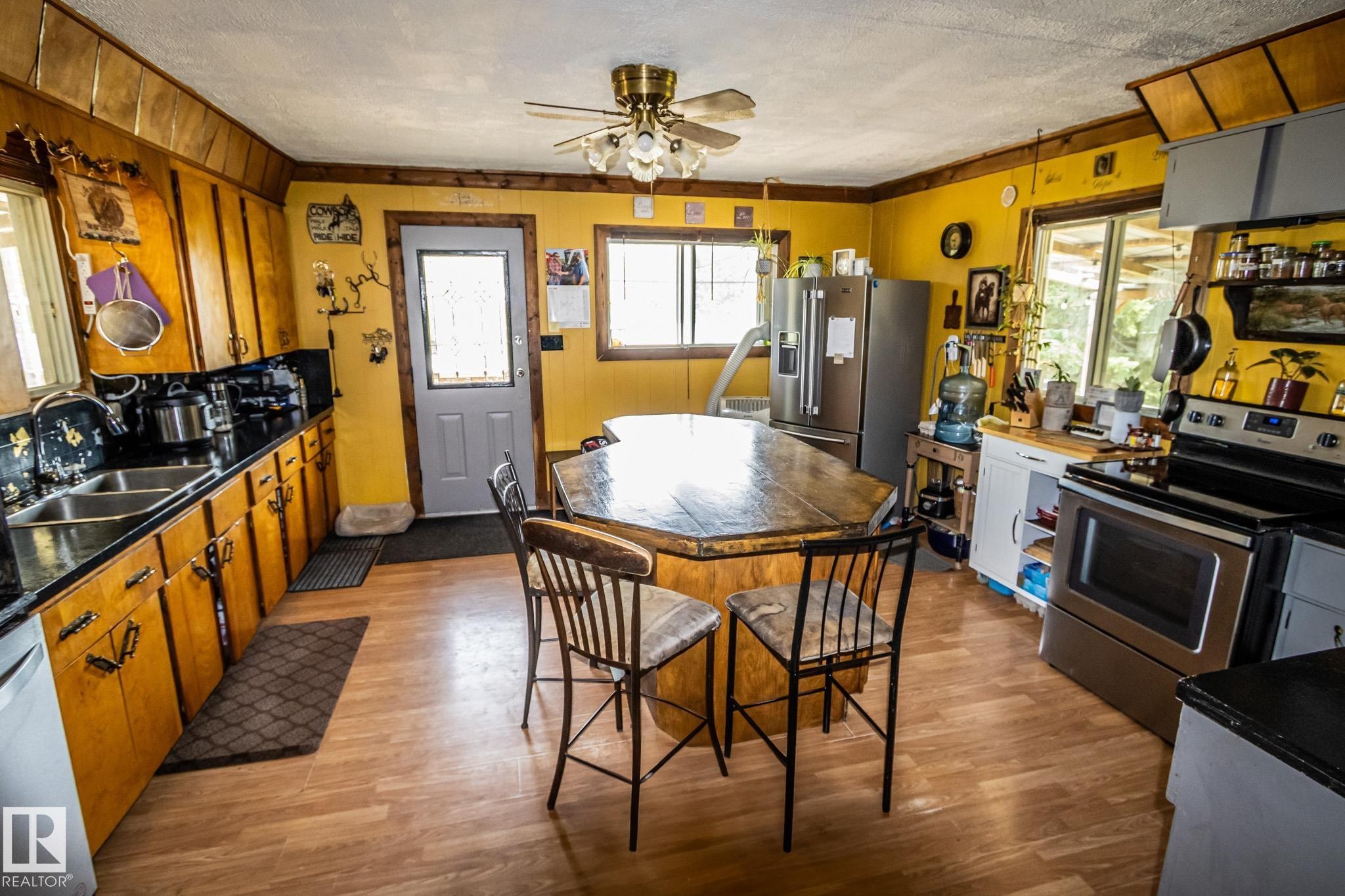Kitchen featuring wood-finish flooring, a central island with a wood-finish countertop, and overhead wood cabinetry - 11218 Twp Rd 590, Rural St. Paul County, AB - Indoor Photo Showing Kitchen With Double Sink