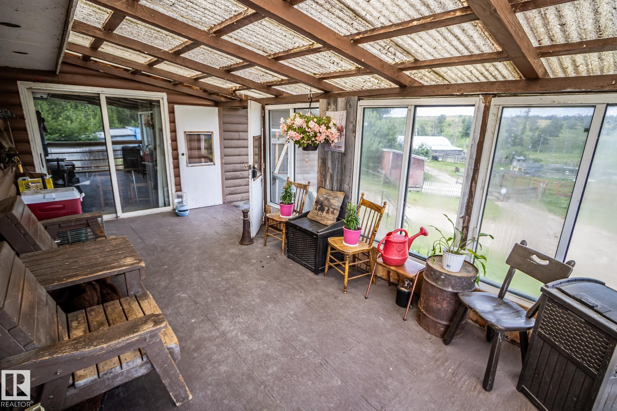 Enclosed porch area featuring a translucent corrugated roof, wood-paneled walls, and multiple large windows - 11218 Twp Rd 590, Rural St. Paul County, AB -