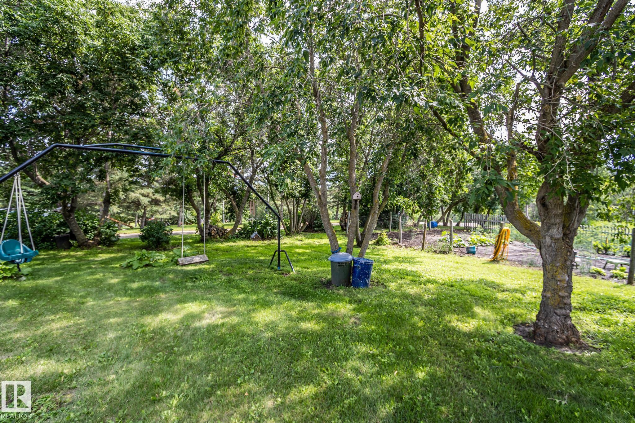 Expansive green lawn with mature trees and a dedicated garden area - 11218 Twp Rd 590, Rural St. Paul County, AB - Outdoor