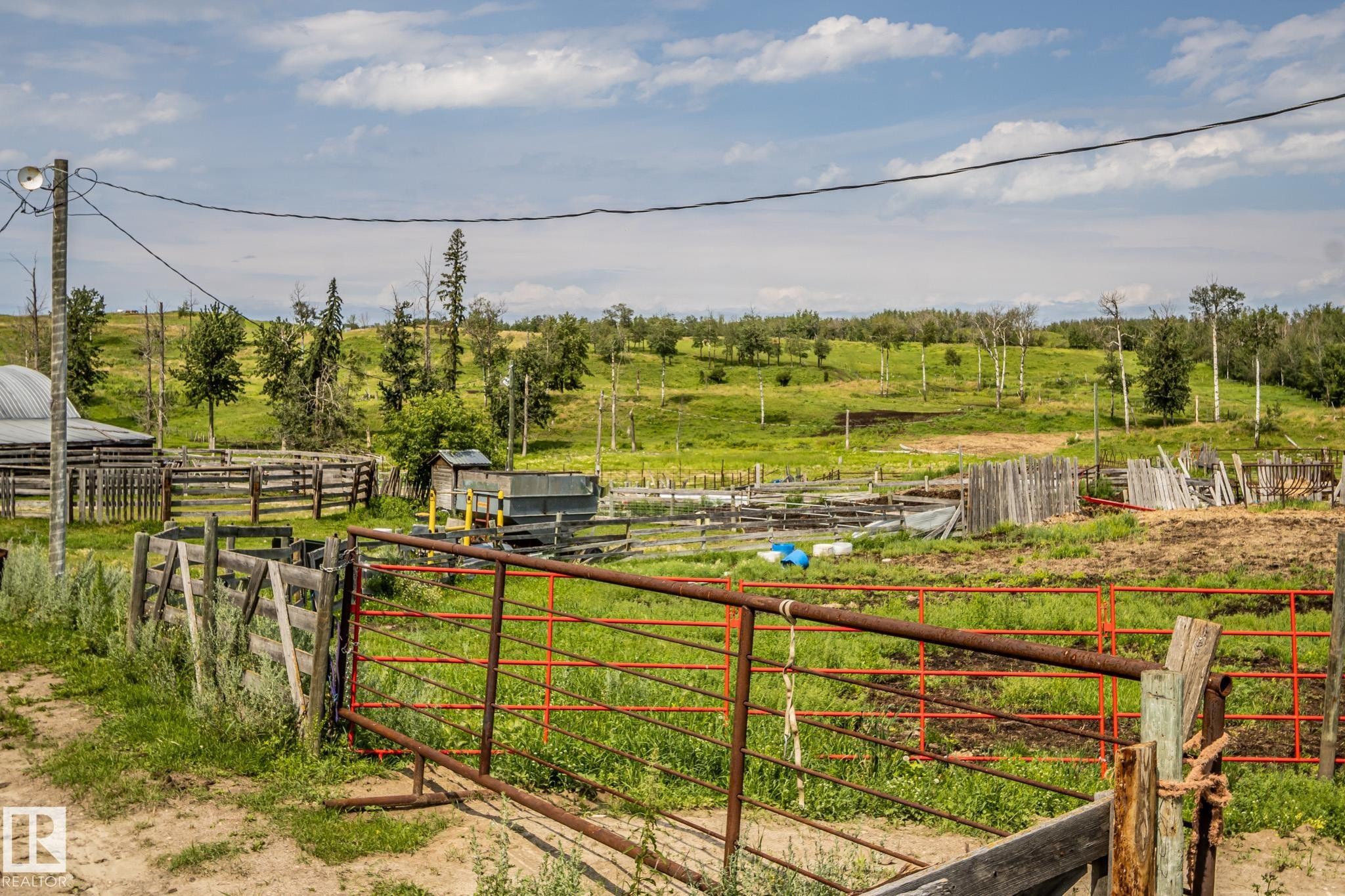 Expansive rural property featuring multiple functional outbuildings, sturdy post-and-rail fencing, and open pastureland with scattered mature tree coverage - 11218 Twp Rd 590, Rural St. Paul County, AB - Outdoor With View