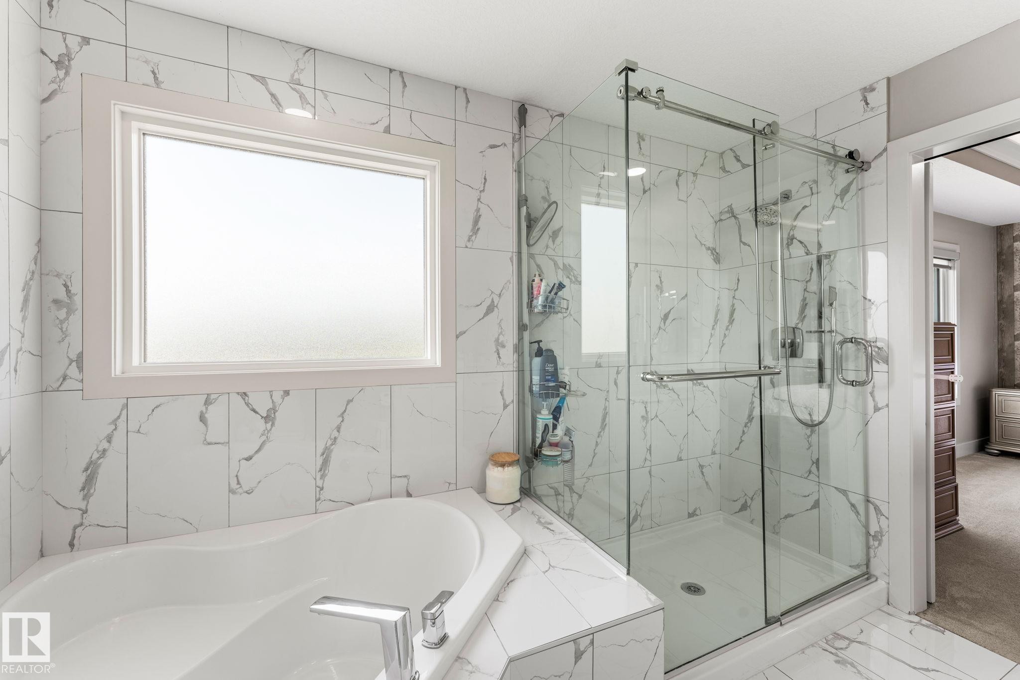 Bathroom featuring a corner soaking tub with deck-mounted chrome fixtures, a large frosted window, and an adjacent glass-enclosed shower with subway-tiled walls - 12383 176 Avenue Nw, Edmonton, AB - Indoor Photo Showing Bathroom