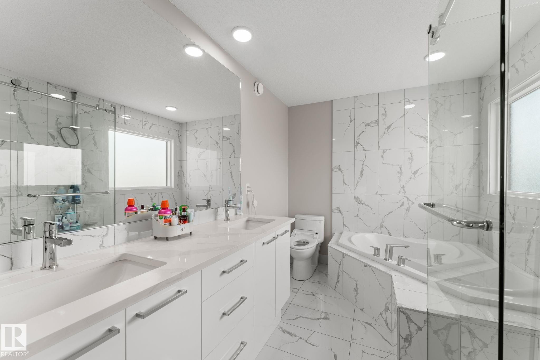 Bathroom featuring a dual vanity with undermount sinks, a corner soaking tub, and a separate glass-enclosed shower - 12383 176 Avenue Nw, Edmonton, AB - Indoor Photo Showing Bedroom