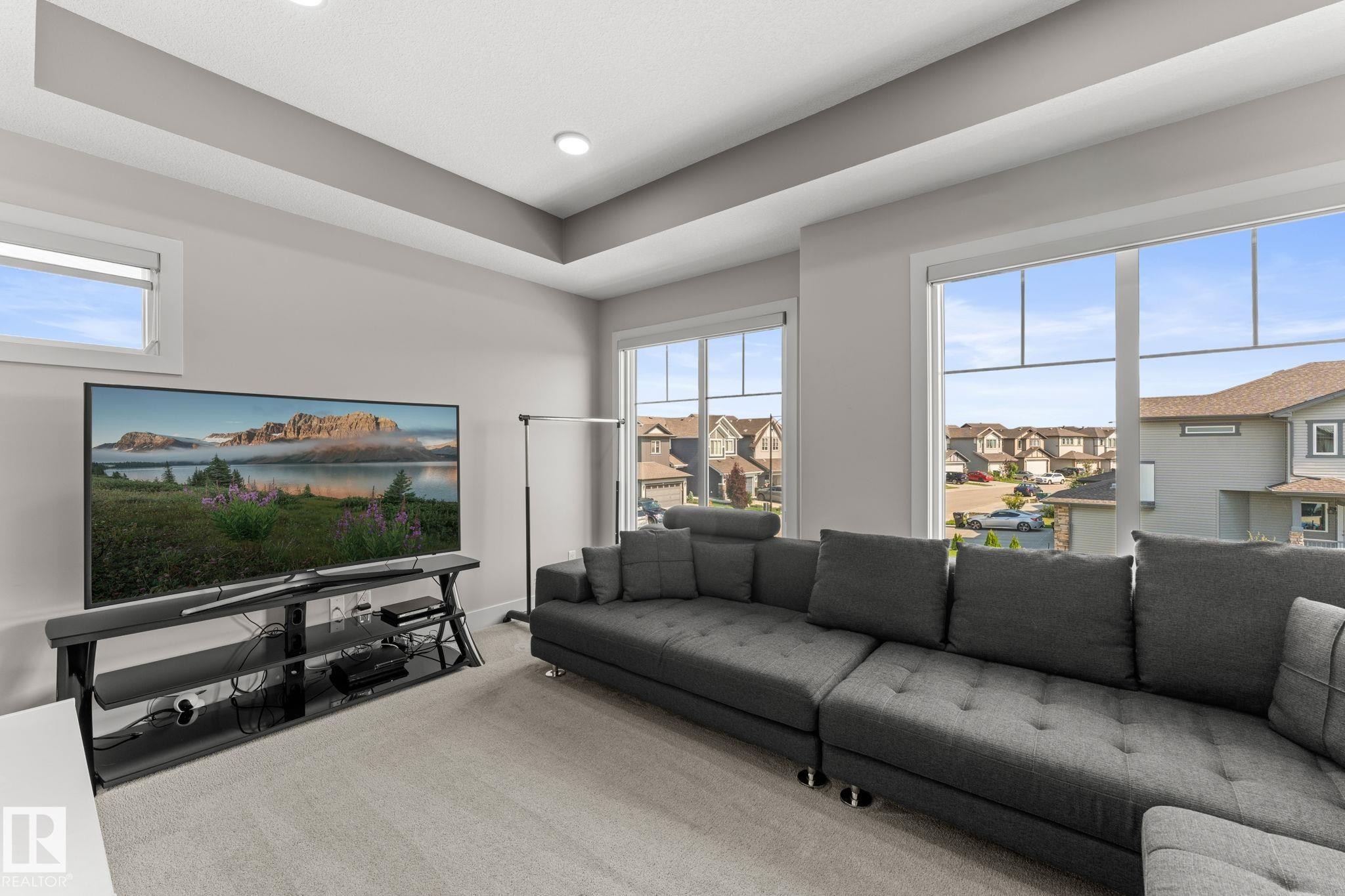 Spacious room with light gray walls, plush carpeting, large windows, and a tray ceiling with recessed lighting - 12383 176 Avenue Nw, Edmonton, AB - Indoor Photo Showing Living Room