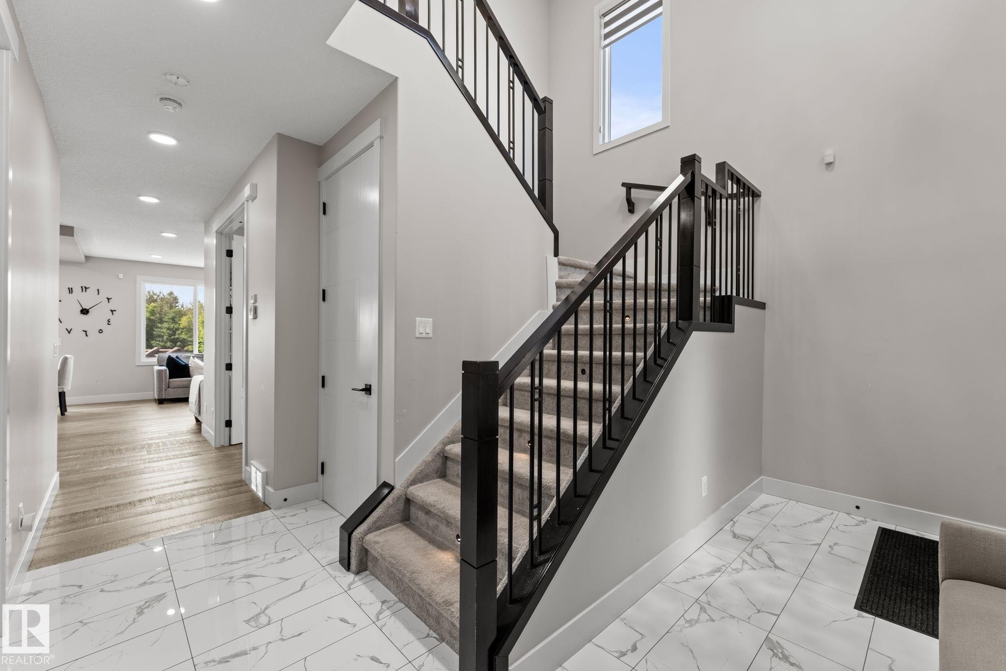 Staircase with dark wood newel posts and railings, black metal spindles, and carpeted treads - 12383 176 Avenue Nw, Edmonton, AB - Indoor Photo Showing Other Room