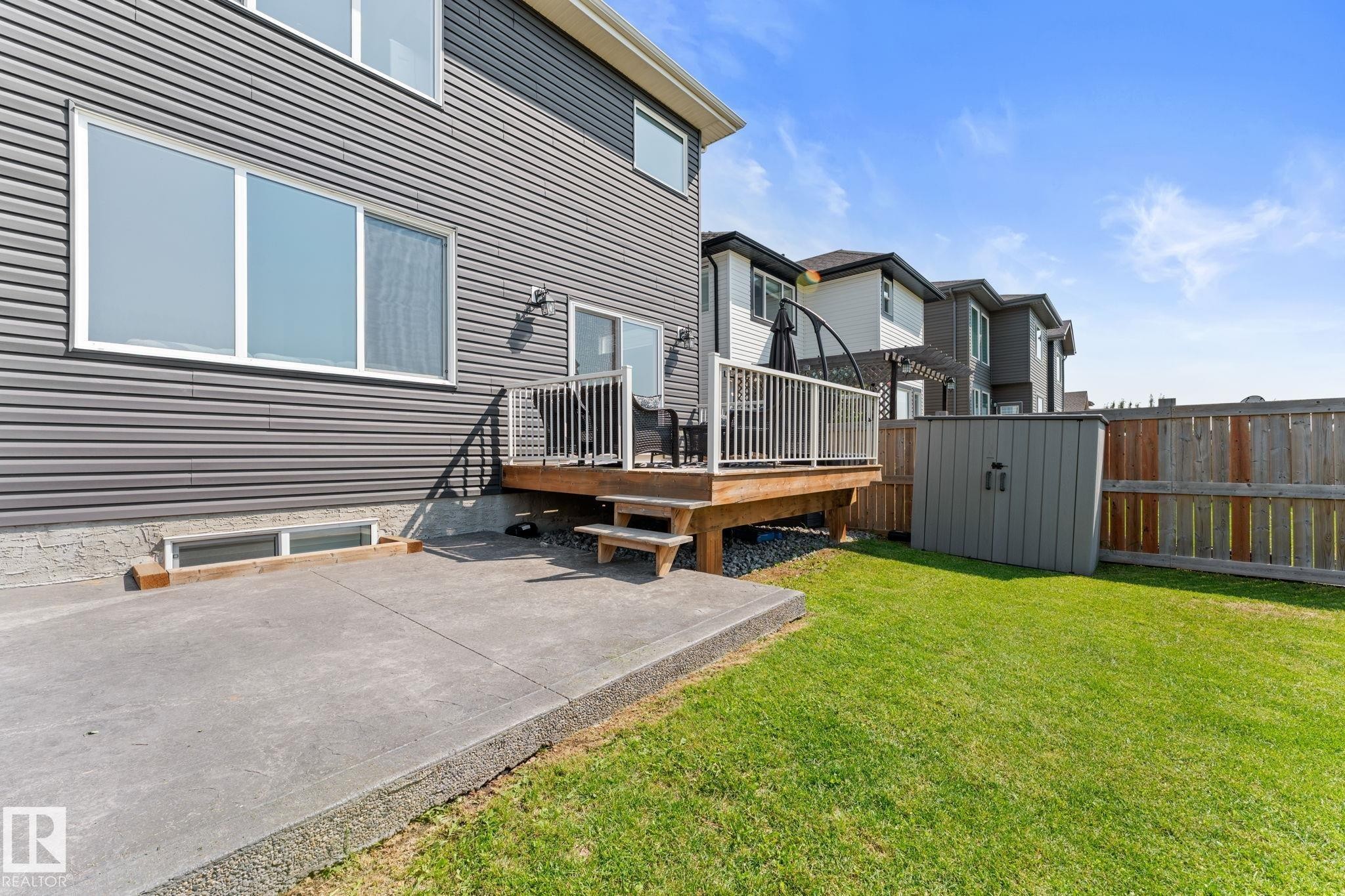 Fenced backyard featuring a concrete patio, wooden deck with white railing, and a storage shed - 12383 176 Avenue Nw, Edmonton, AB - Outdoor
