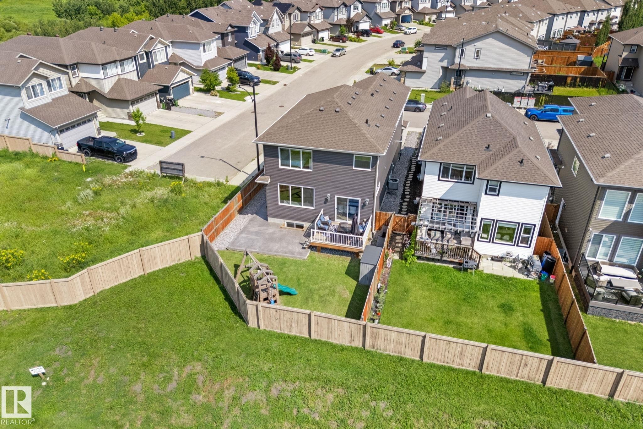 Rear elevation of a two-story residence featuring a ground-level patio with a wooden deck - 12383 176 Avenue Nw, Edmonton, AB - Other