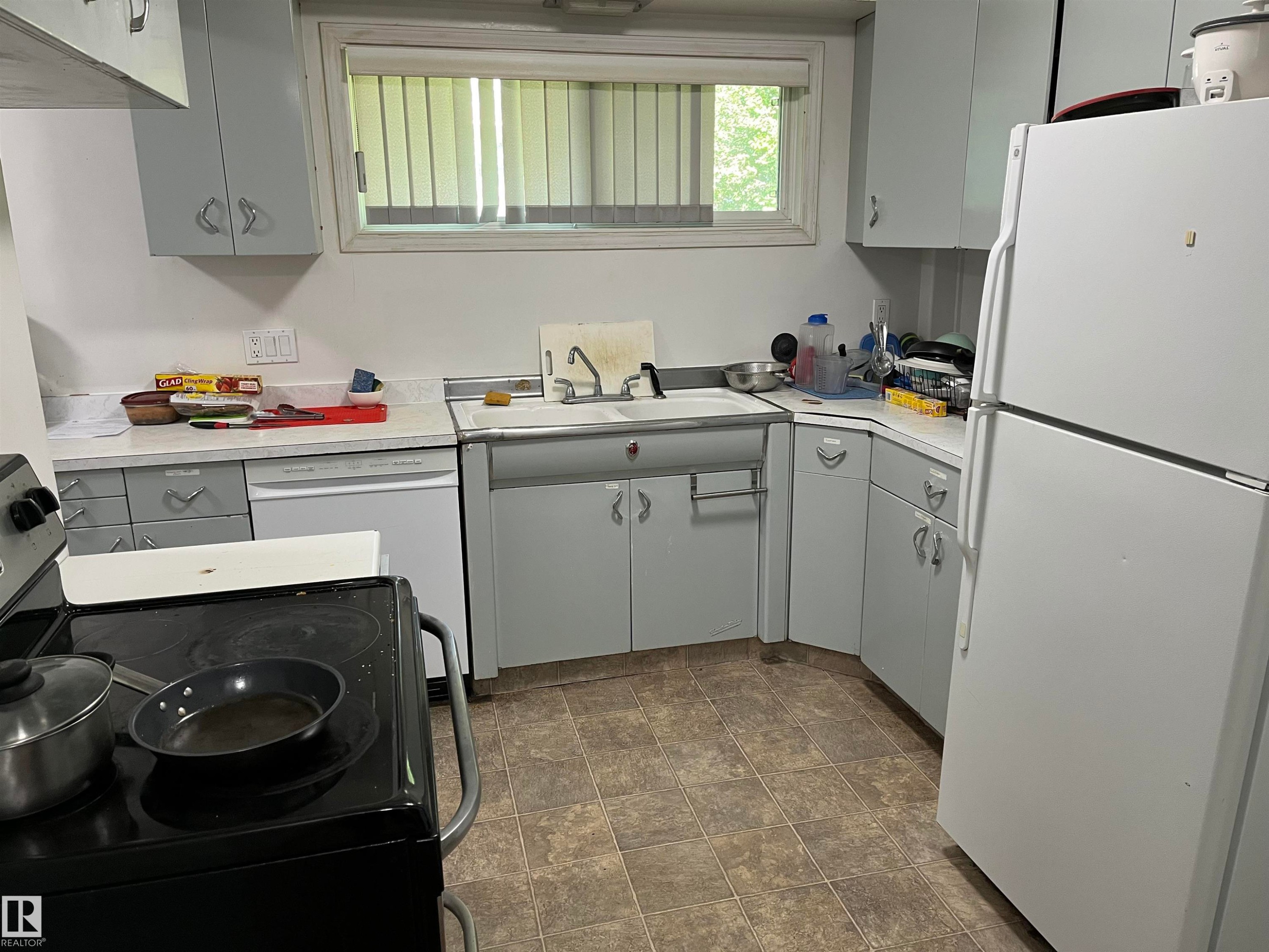Kitchen featuring light gray cabinetry, white countertops, a built-in dishwasher, white refrigerator, and a window with horizontal blinds - 12011 87 Avenue Nw, Edmonton, AB - Indoor Photo Showing Laundry Room