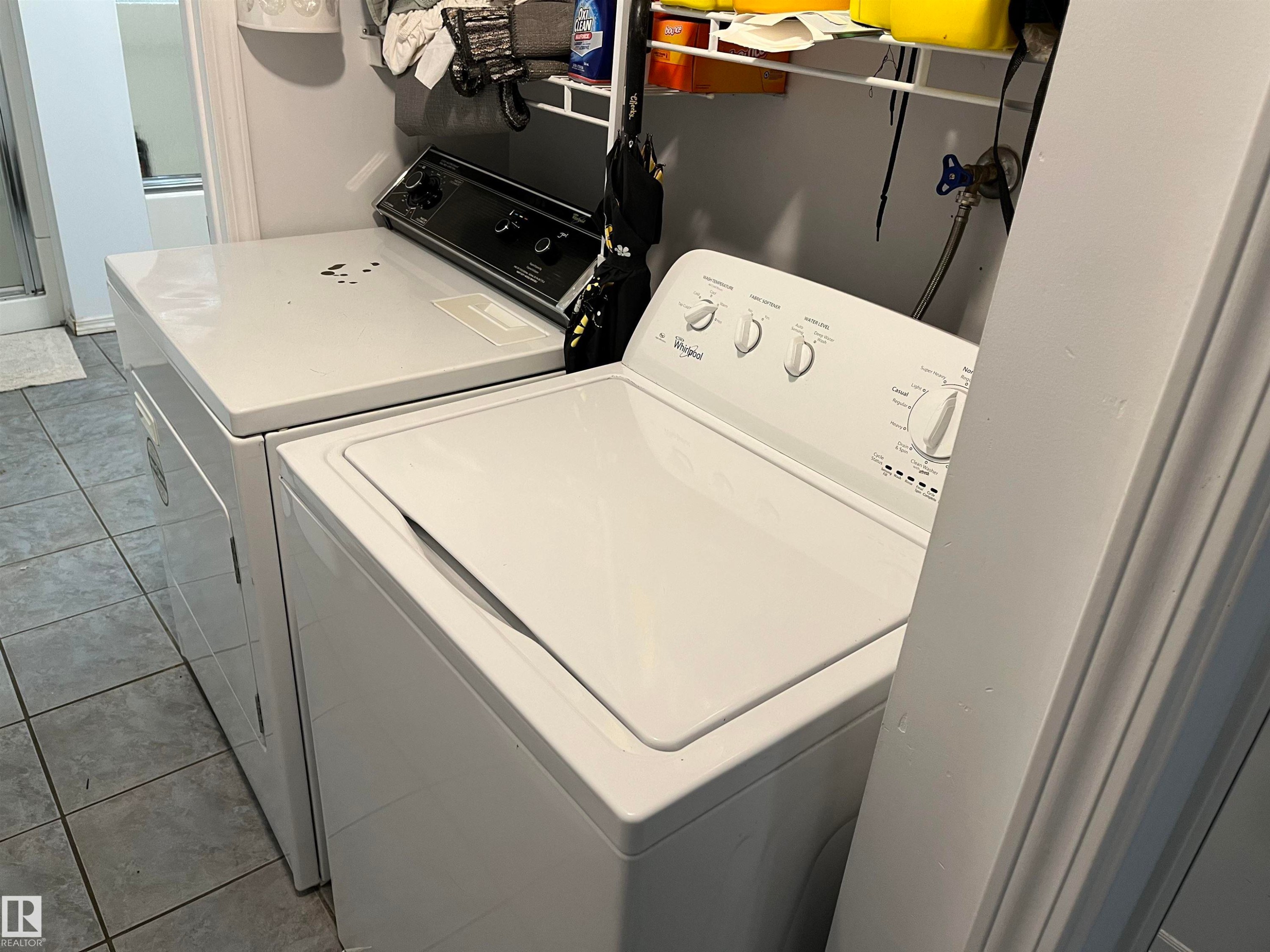 Laundry room featuring side-by-side washer and dryer units with white finish, complemented by white cabinetry and tile flooring - 12011 87 Avenue Nw, Edmonton, AB - Indoor Photo Showing Laundry Room