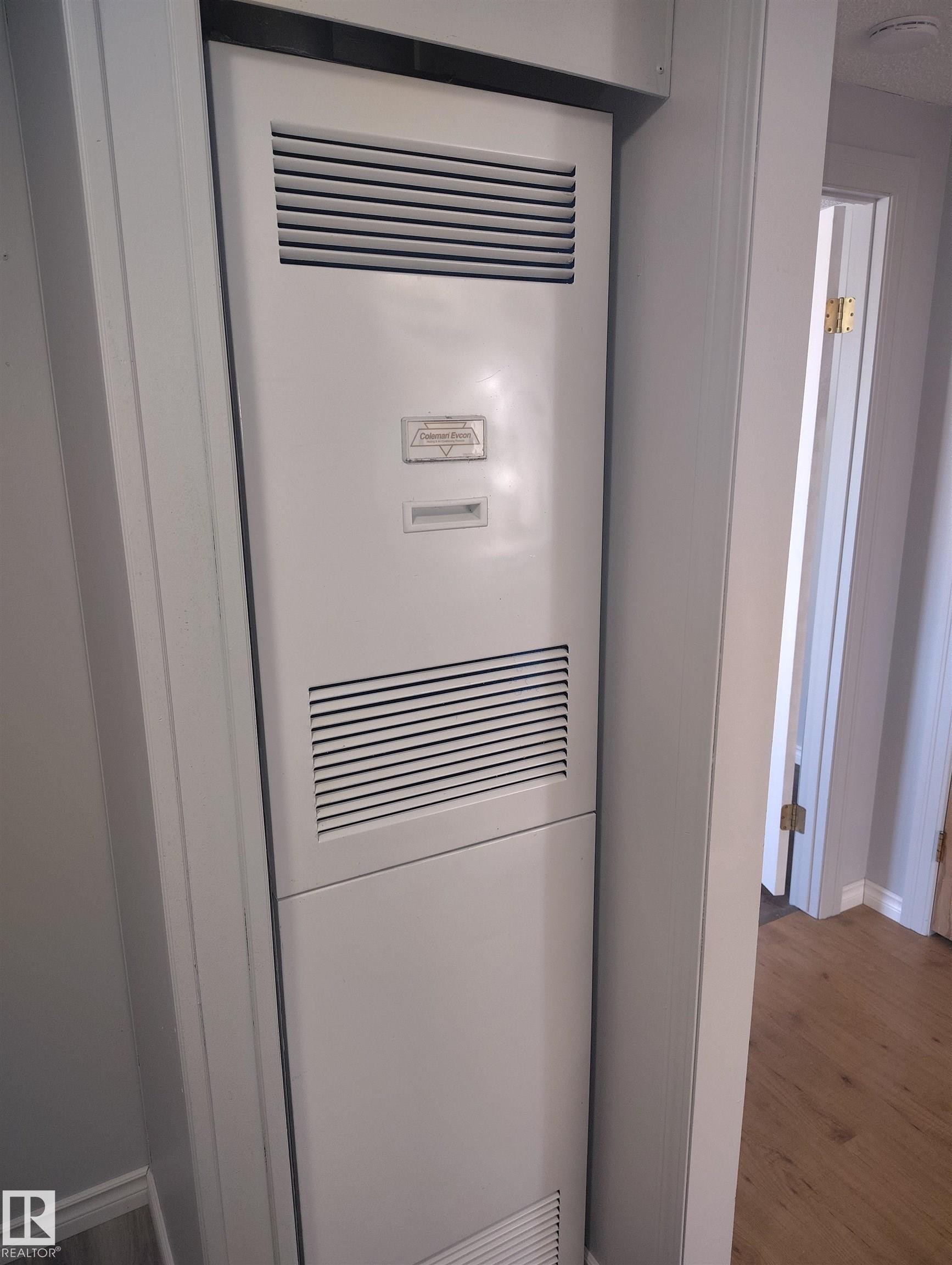 Vertical heating unit with white paneling and horizontal vents, recessed within a light gray wall - 42 Midland Road, Millet, AB - Indoor Photo Showing Basement
