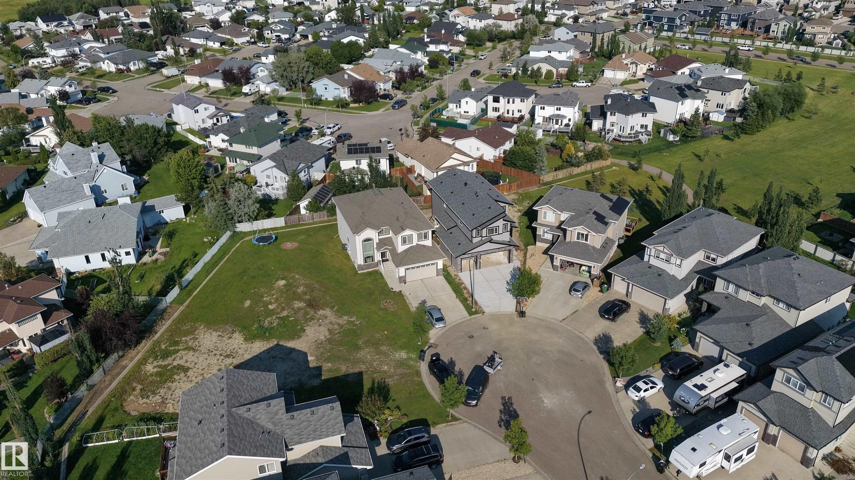 Residential cul-de-sac with multiple detached properties, surrounded by green spaces and paved streets - 34 Mckenzie Close Close, Leduc, AB - Outdoor With View