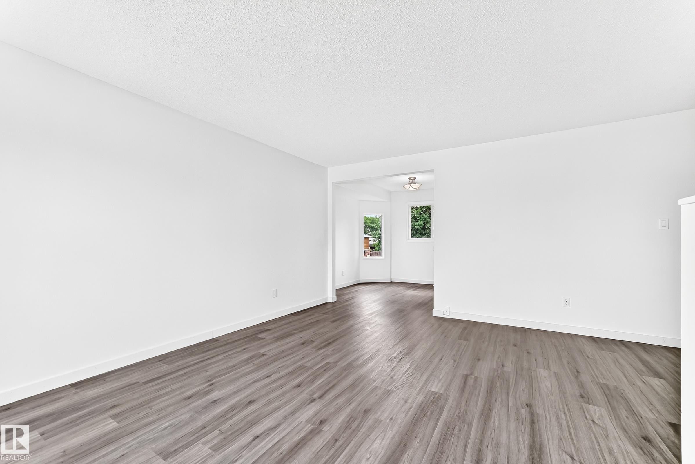 Spacious room featuring wood-finish flooring, crisp white walls, and bright white baseboards - 5519 142 Avenue Nw, Edmonton, AB - Indoor Photo Showing Other Room