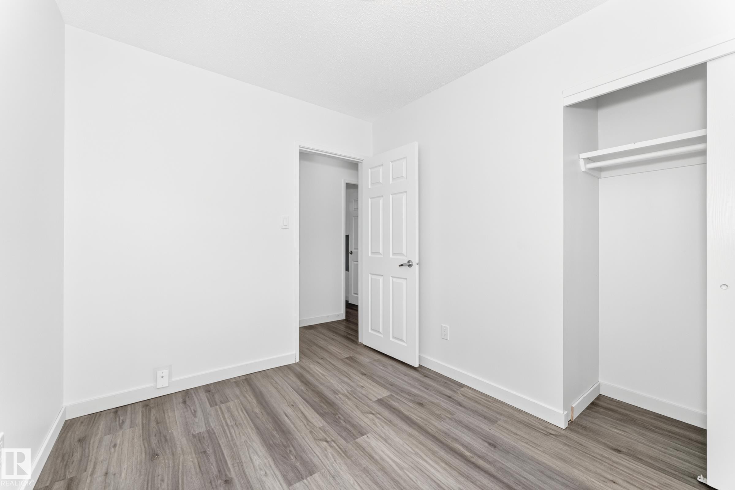 Neutral white walls and wood-finish flooring define this interior space - 5519 142 Avenue Nw, Edmonton, AB - Indoor Photo Showing Other Room