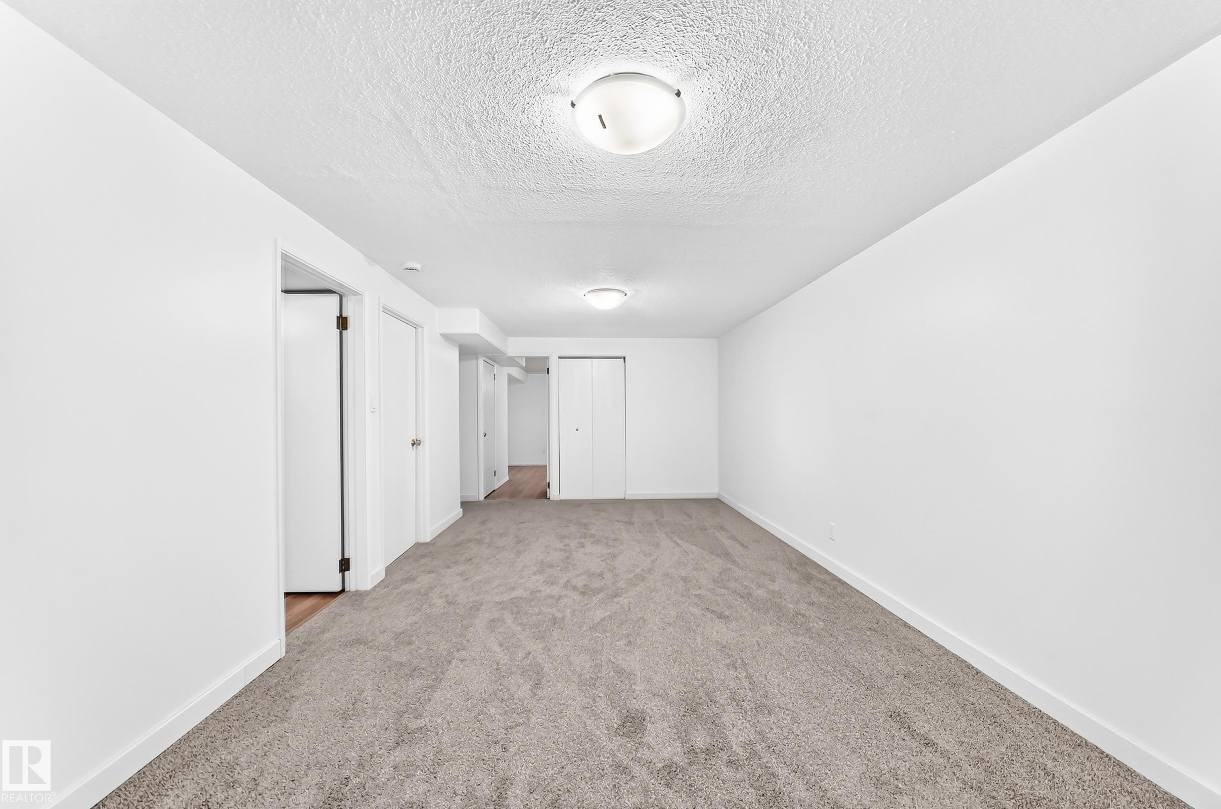 Neutral-toned wall-to-wall carpeting complements the white walls and trim - 5519 142 Avenue Nw, Edmonton, AB - Indoor Photo Showing Other Room