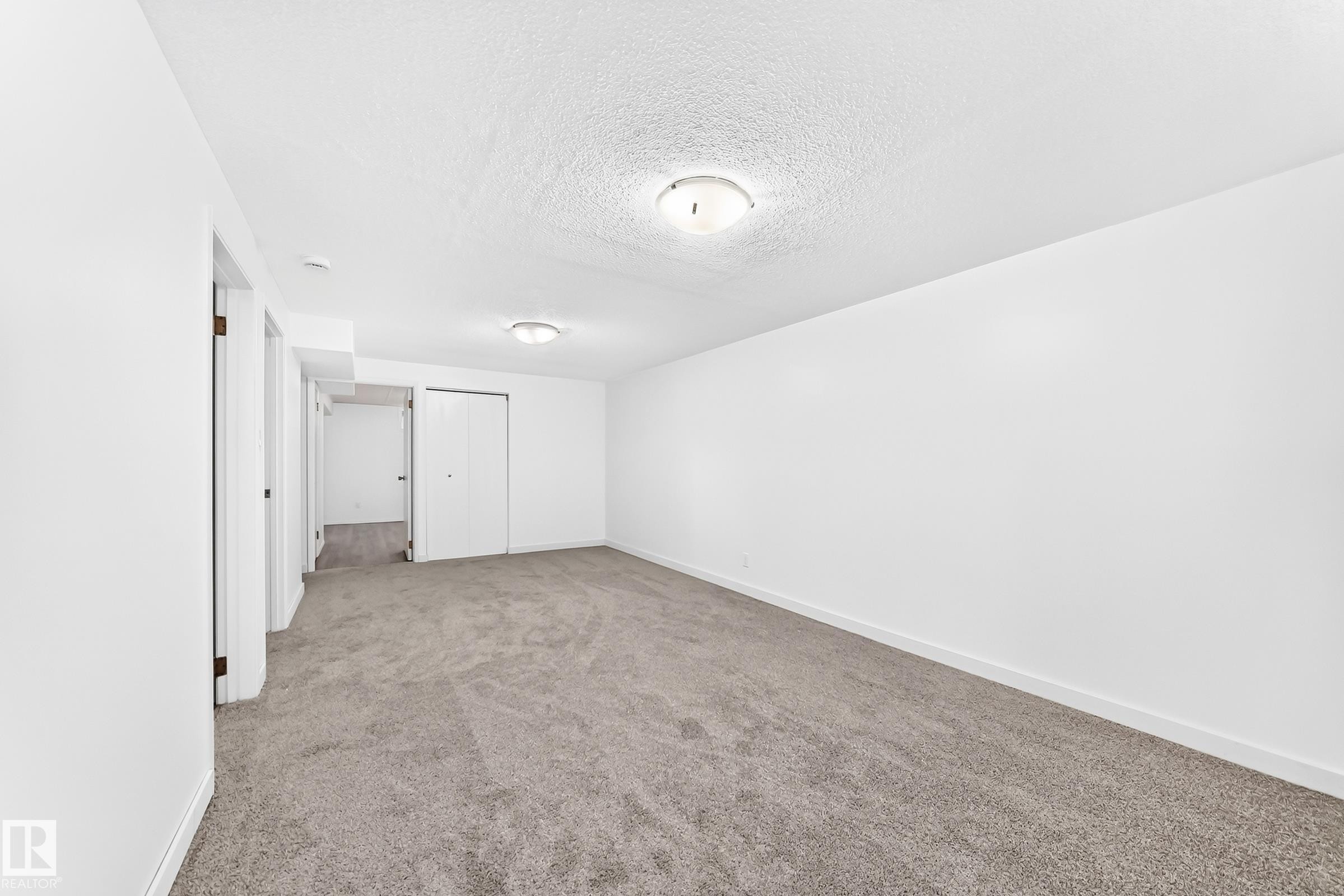 Spacious room featuring neutral carpeting, white walls, and bright overhead lighting - 5519 142 Avenue Nw, Edmonton, AB - Indoor Photo Showing Other Room