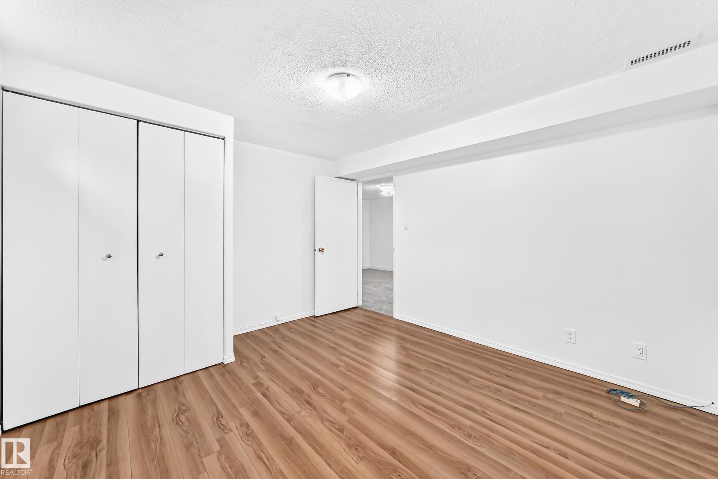 Room featuring wood-finish flooring, white walls, and a textured ceiling - 5519 142 Avenue Nw, Edmonton, AB - Indoor Photo Showing Other Room