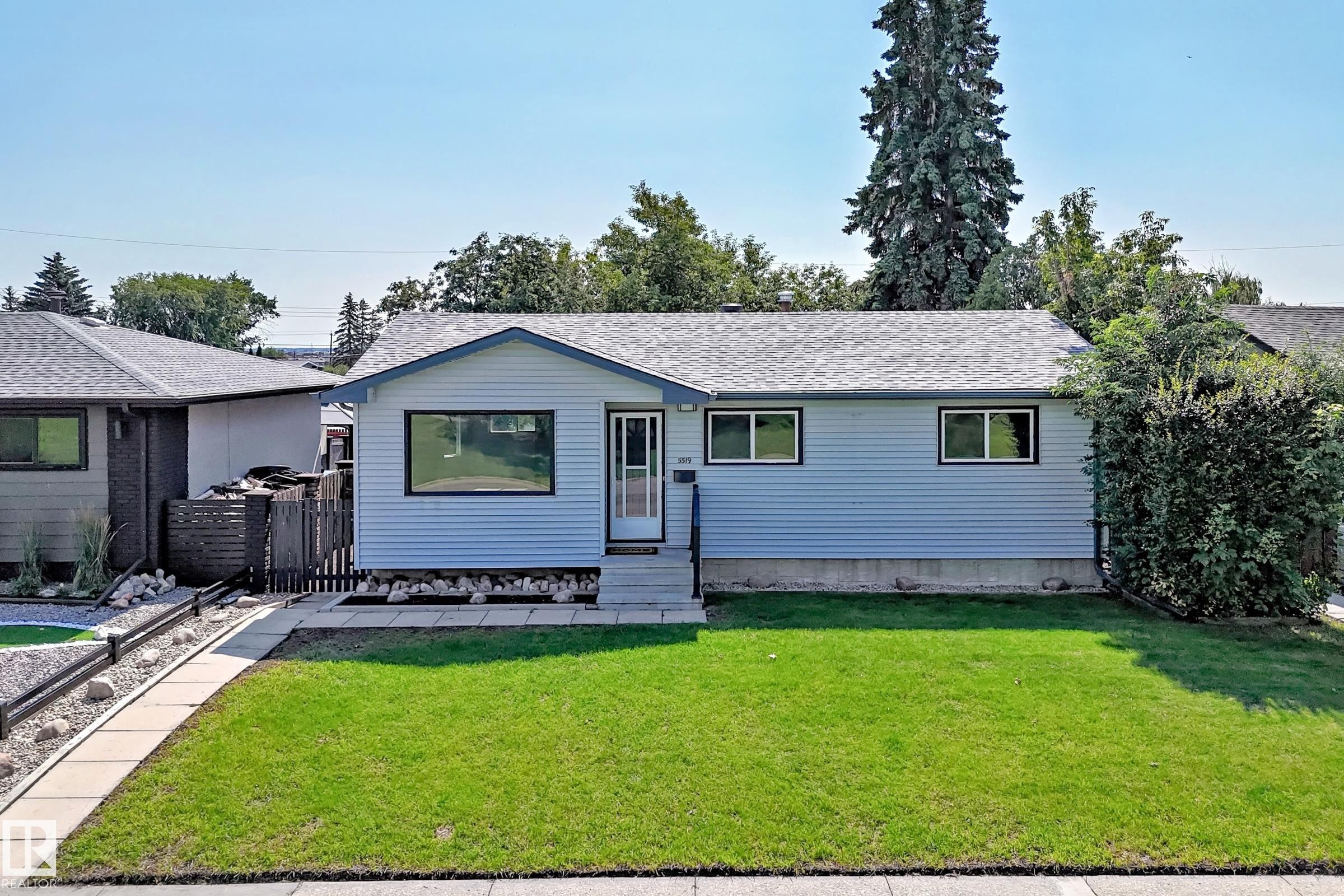 Light blue siding exterior with dark-trimmed windows and a gray shingle roof - 5519 142 Avenue Nw, Edmonton, AB - Outdoor
