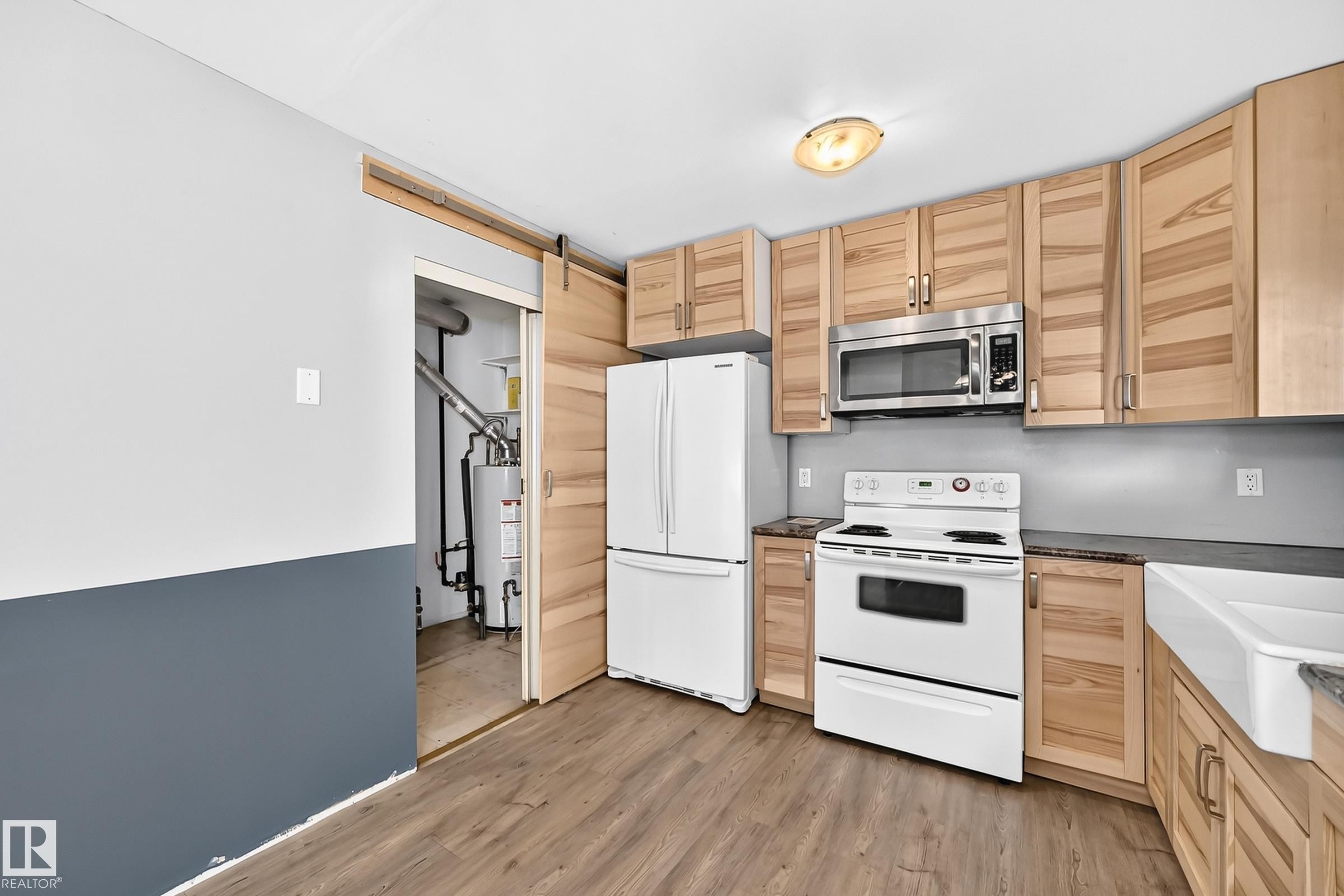 Kitchen featuring wood-finish cabinetry, stainless steel microwave, white electric range, and a white farmhouse-style sink - 290 Lancaster Terrace Nw, Edmonton, AB - Indoor Photo Showing Kitchen