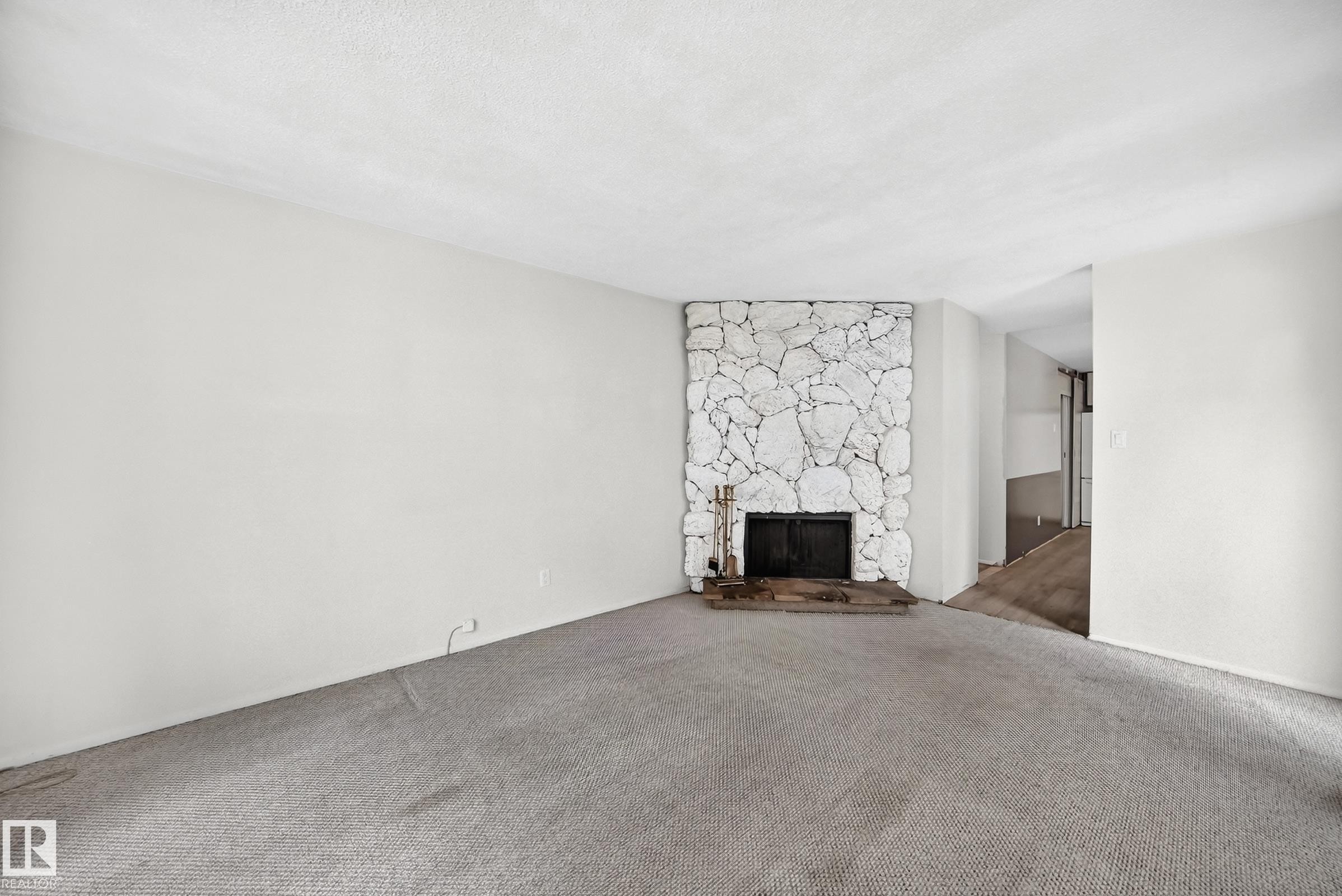 Stone-clad fireplace with a black firebox and hearth - 290 Lancaster Terrace Nw, Edmonton, AB - Indoor Photo Showing Other Room With Fireplace