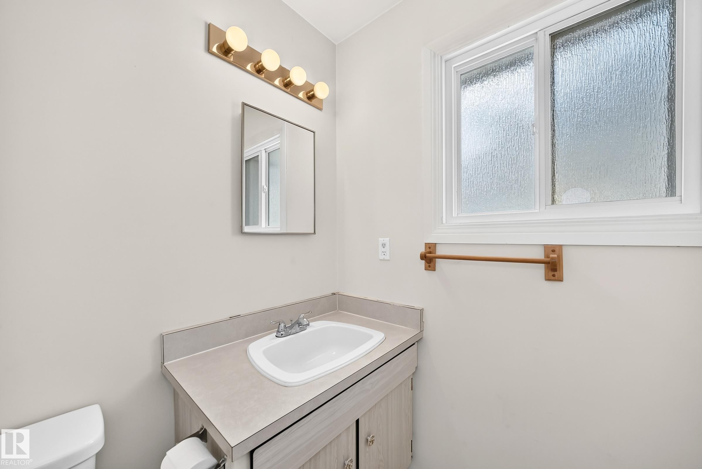 Bathroom vanity with integrated sink, laminate countertop, and wood-finish cabinetry - 290 Lancaster Terrace Nw, Edmonton, AB - Indoor Photo Showing Bathroom
