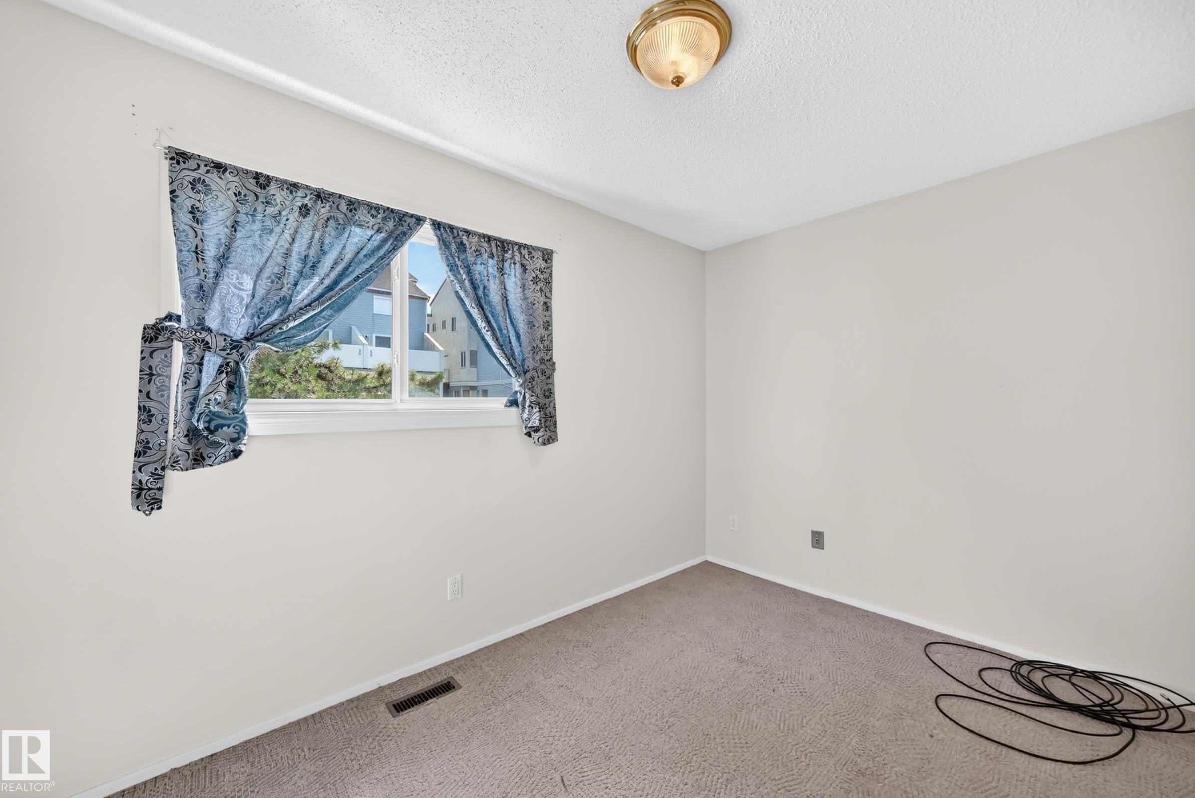 Bright interior room featuring a window with natural light, light-colored walls, and a ceiling-mounted light fixture - 290 Lancaster Terrace Nw, Edmonton, AB - Indoor Photo Showing Other Room