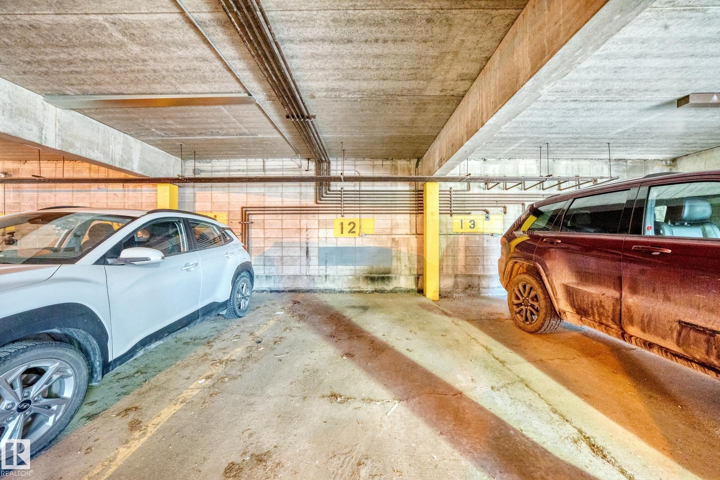 Underground parking space featuring concrete flooring and ceiling, industrial piping, and yellow support beams - 290 Lancaster Terrace Nw, Edmonton, AB - Indoor Photo Showing Garage