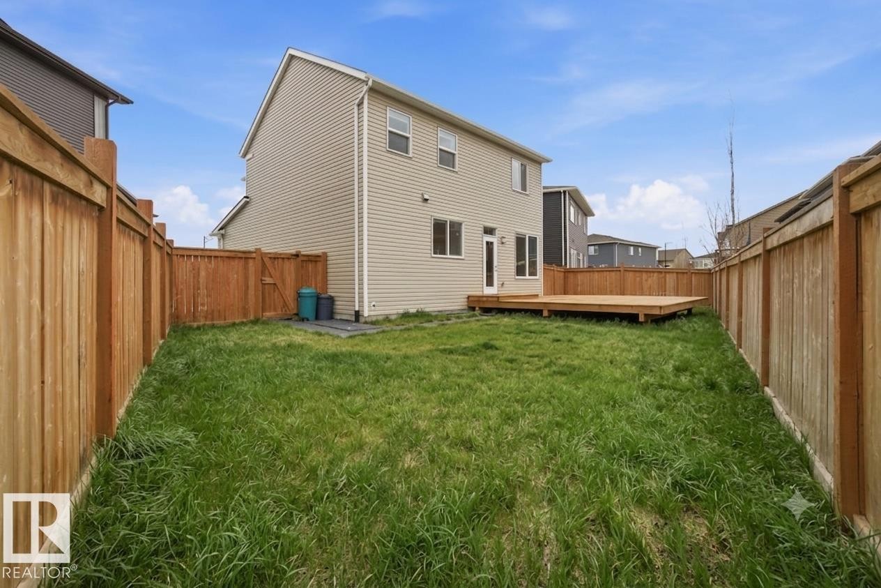 Expansive backyard featuring a manicured lawn, full wood fencing, and a large wood deck - 1607 202 Street Nw, Edmonton, AB - Outdoor With Deck Patio Veranda With Exterior