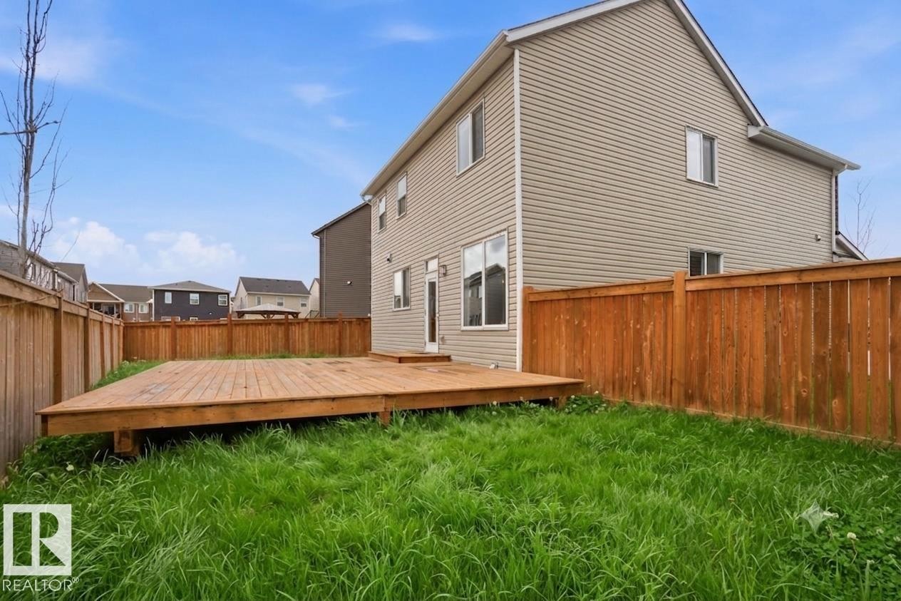Backyard featuring a spacious wood deck, privacy fencing, and a grass area - 1607 202 Street Nw, Edmonton, AB - Outdoor With Deck Patio Veranda