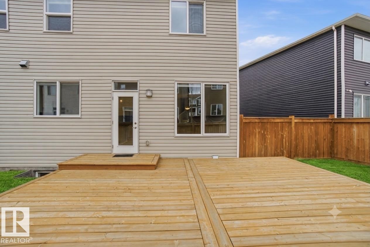 Expansive wooden deck with a privacy fence and a grassy yard area - 1607 202 Street Nw, Edmonton, AB - Outdoor With Exterior