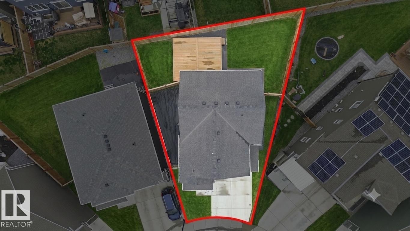 Aerial view highlighting the property's boundaries, featuring a substantial backyard lawn, a wood-finish deck, and a concrete driveway - 1607 202 Street Nw, Edmonton, AB - Other