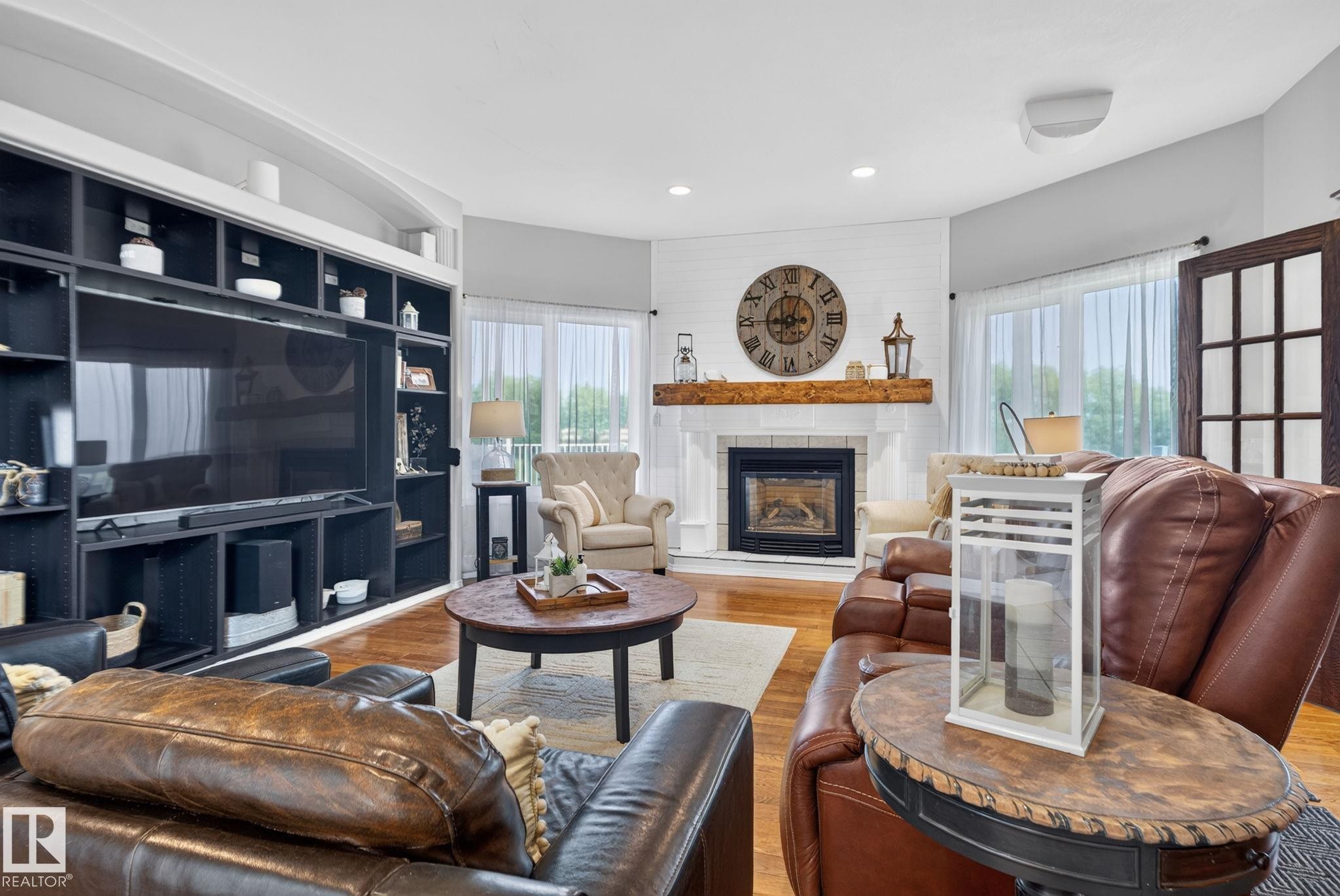 Living area featuring hardwood-finish flooring, a built-in media center with shelving, a shiplap accent wall, and a fireplace with a wood mantle - 50336 Range Road 280, Rural Leduc County, AB - Indoor Photo Showing Living Room With Fireplace
