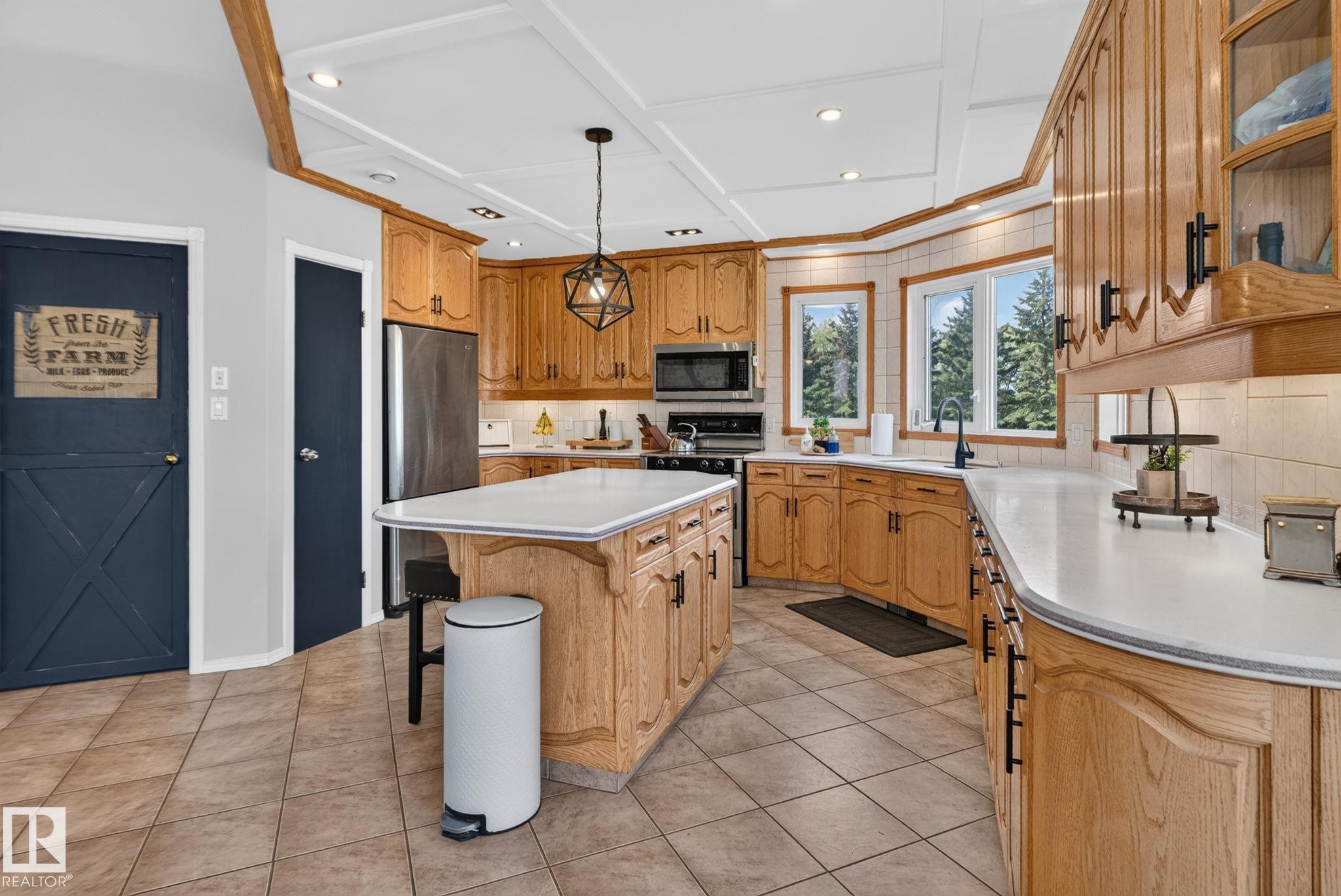 Kitchen featuring light wood cabinetry, white countertops, stainless steel appliances, a center island with seating, and tiled flooring - 50336 Range Road 280, Rural Leduc County, AB - Indoor Photo Showing Kitchen With Double Sink