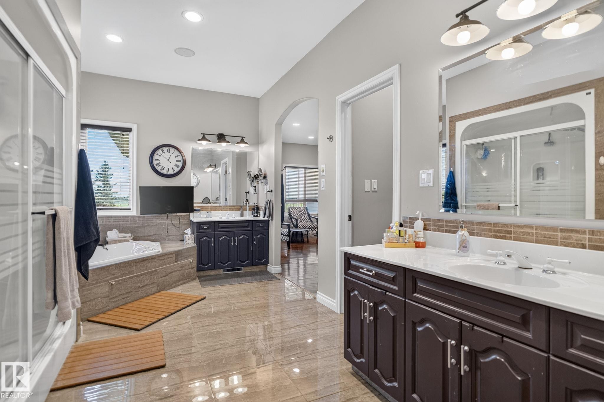 Spacious bathroom featuring a dual vanity with white countertops, a deep soaking tub, a separate glass-enclosed shower, and large format tile flooring - 50336 Range Road 280, Rural Leduc County, AB - Indoor Photo Showing Bathroom