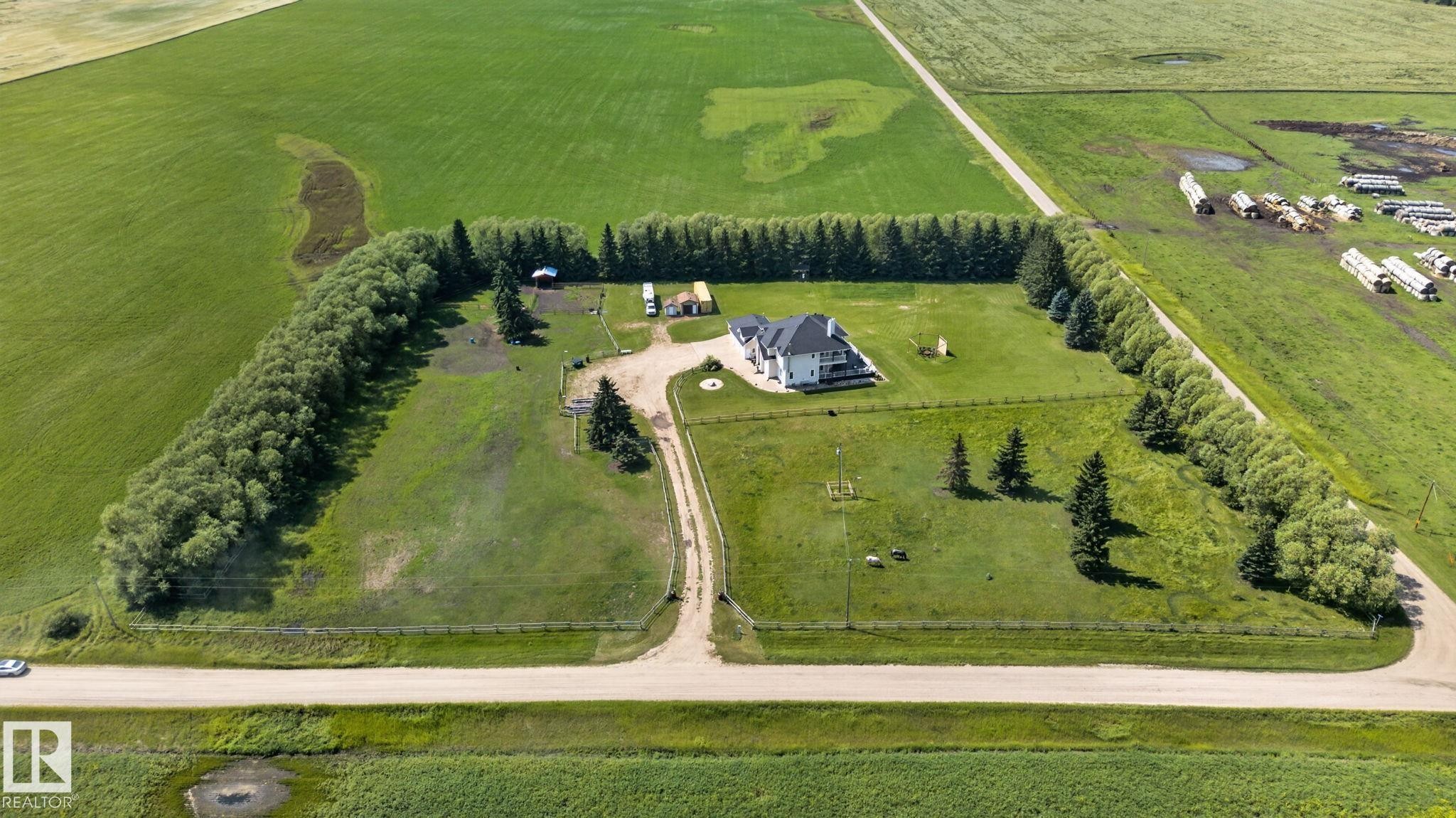 Aerial perspective showcasing a large residential property surrounded by expansive green fields - 50336 Range Road 280, Rural Leduc County, AB - Outdoor With View