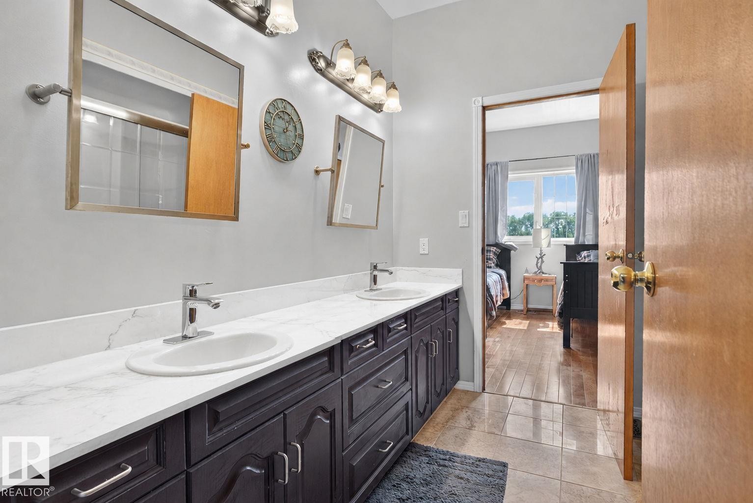 Double vanity featuring dark wood cabinetry, white countertops, and dual undermount sinks with chrome faucets - 50336 Range Road 280, Rural Leduc County, AB - Indoor Photo Showing Bathroom