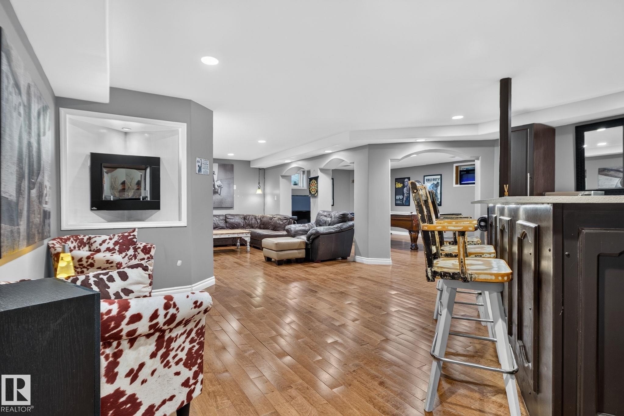 Spacious entertainment area featuring wood-finish flooring, recessed lighting, and a built-in wall niche with an inset fireplace - 50336 Range Road 280, Rural Leduc County, AB - Indoor