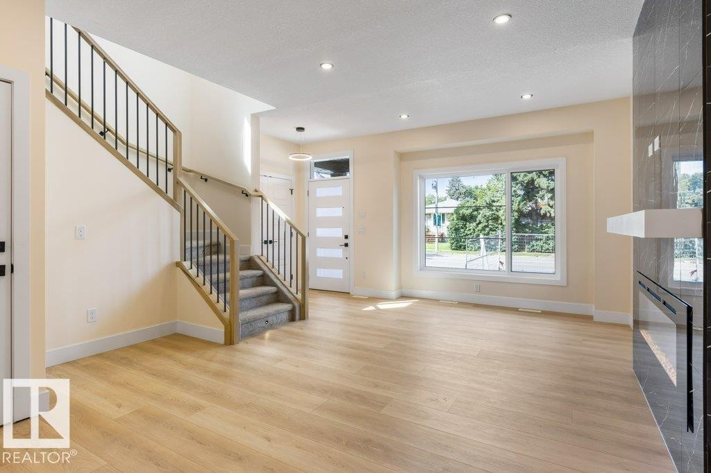 Bright and spacious open-concept living area featuring gleaming wood-finish flooring, recessed ceiling lighting, and abundant natural light from expansive windows - 10323 79 Street Nw, Edmonton, AB - Indoor Photo Showing Other Room