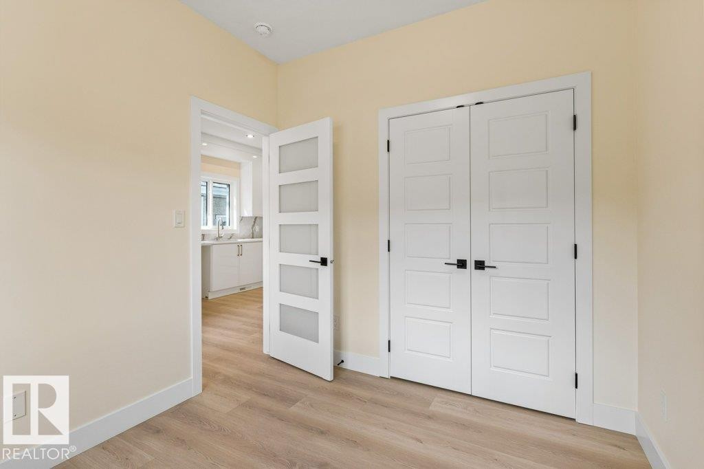 Bedroom 1 - Bright bedroom featuring gleaming wood-finish flooring, soft neutral wall tones, and abundant natural light - 10323 79 Street Nw, Edmonton, AB - Indoor Photo Showing Other Room