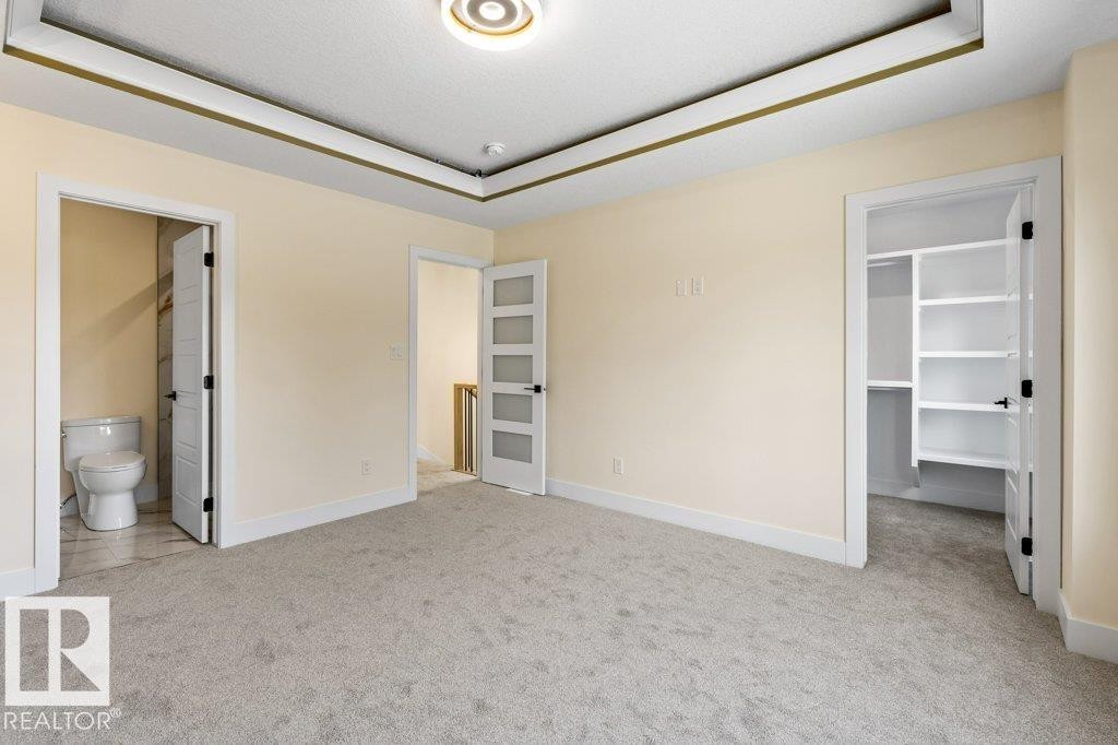Spacious room featuring light-toned walls, grey carpet, and a tray ceiling with recessed lighting - 10323 79 Street Nw, Edmonton, AB - Indoor Photo Showing Other Room