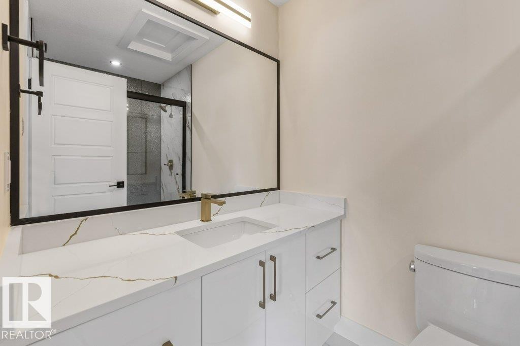 3 Piece Ensuite Bathroom featuring a white vanity with gold-veined countertop, integrated sink, and modern brass-finish faucet - 10323 79 Street Nw, Edmonton, AB - Indoor Photo Showing Bathroom