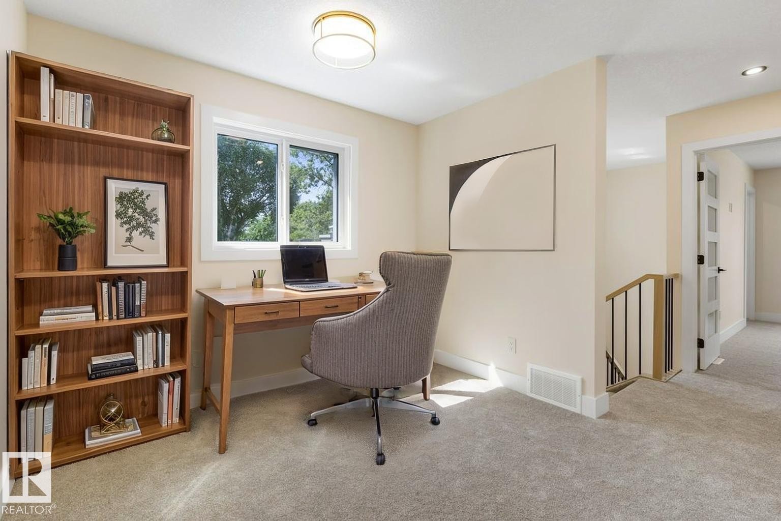 Brightly lit room featuring a large window, light-colored carpeting, and a built-in wooden bookshelf - 10323 79 Street Nw, Edmonton, AB - Indoor Photo Showing Office