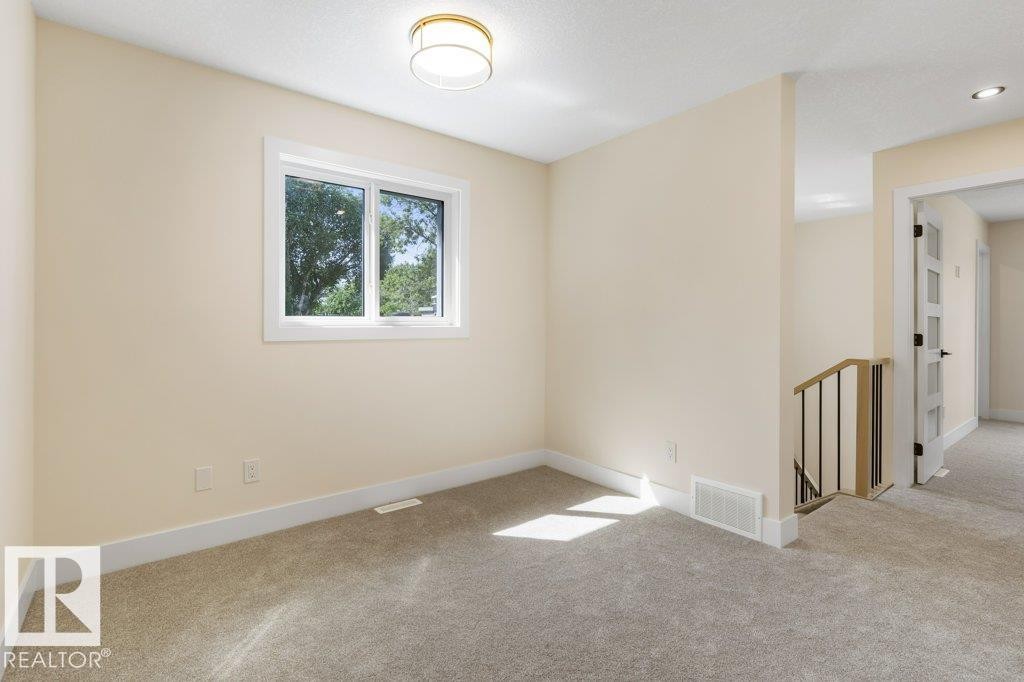 Carpeted room with a double-pane window, neutral-toned walls, white baseboards, and a contemporary ceiling light fixture - 10323 79 Street Nw, Edmonton, AB - Indoor Photo Showing Other Room