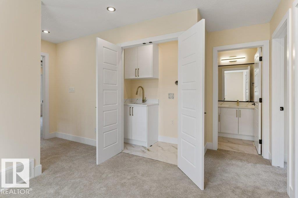 Spacious primary suite featuring a dedicated walk-in closet with double doors, dual vanity bathroom with framed mirror and brushed nickel hardware, neutral wall finishes, and recessed ceiling lighting - 10323 79 Street Nw, Edmonton, AB - Indoor Photo Showing Other Room