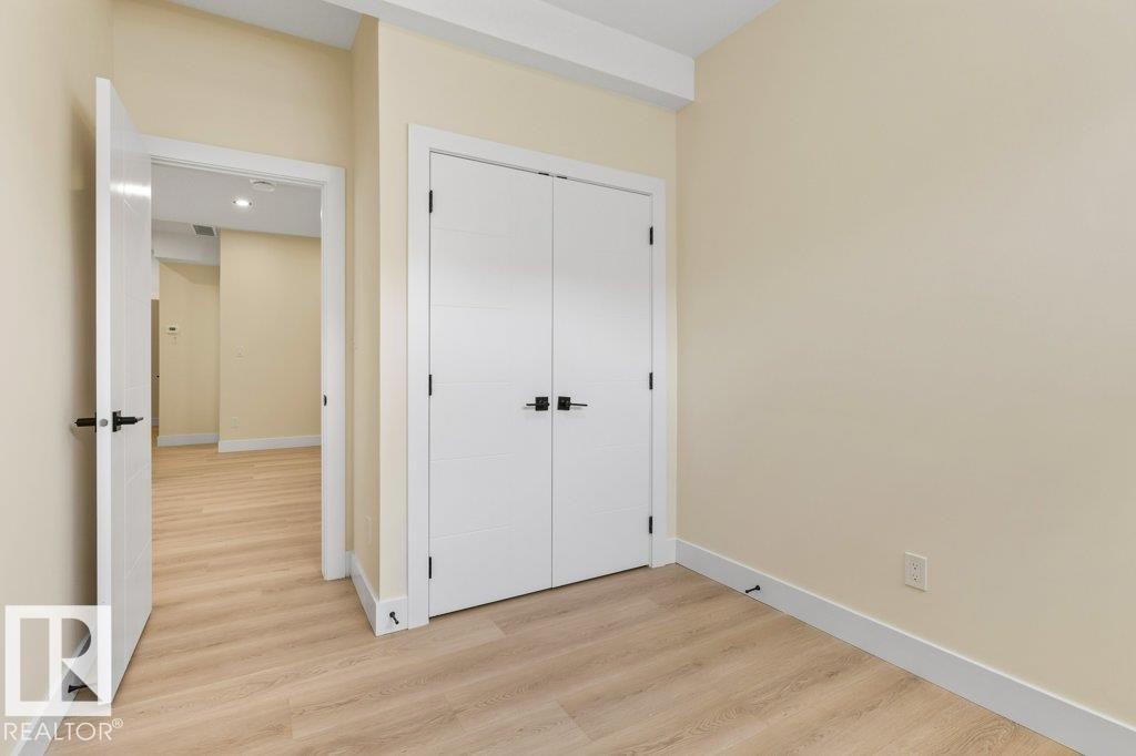 Bedroom 5 - Interior space featuring light-toned walls, wood-finish flooring, and white baseboards - 10323 79 Street Nw, Edmonton, AB - Indoor Photo Showing Other Room