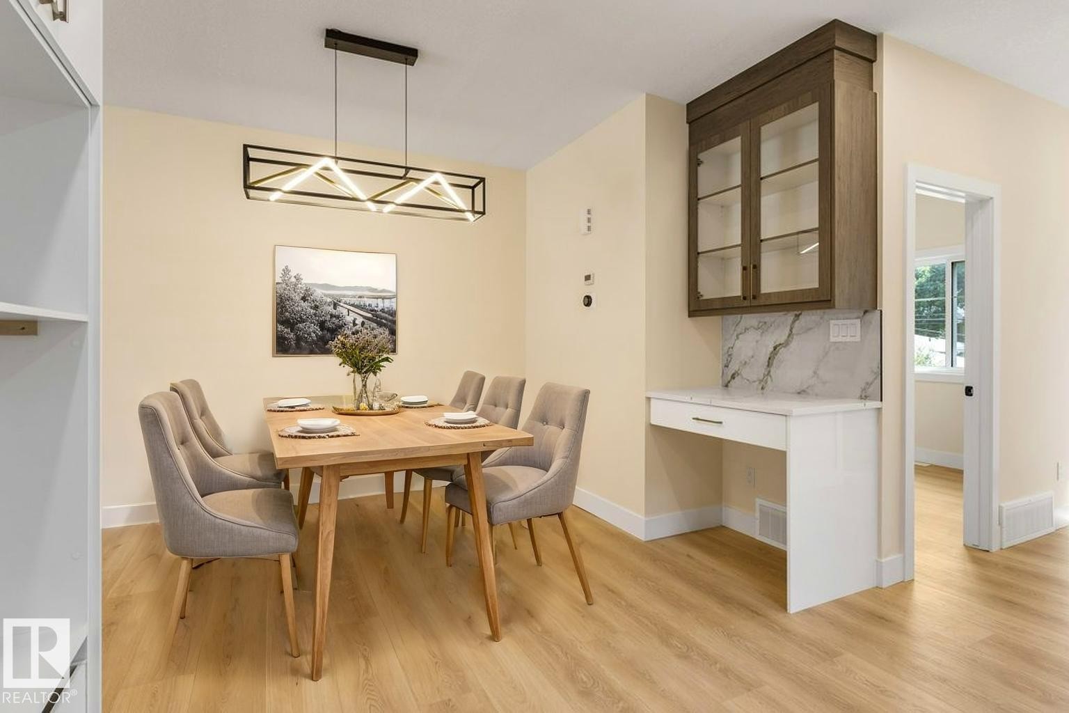 Dining area featuring wood-finish flooring, a contemporary linear chandelier, and a built-in cabinetry unit - 10323 79 Street Nw, Edmonton, AB - Indoor Photo Showing Dining Room