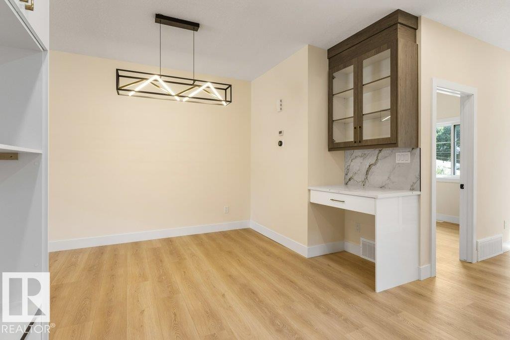 Bright, open dining area showcasing warm wood-finish flooring, recessed lighting, and a geometric pendant fixture - 10323 79 Street Nw, Edmonton, AB - Indoor Photo Showing Other Room